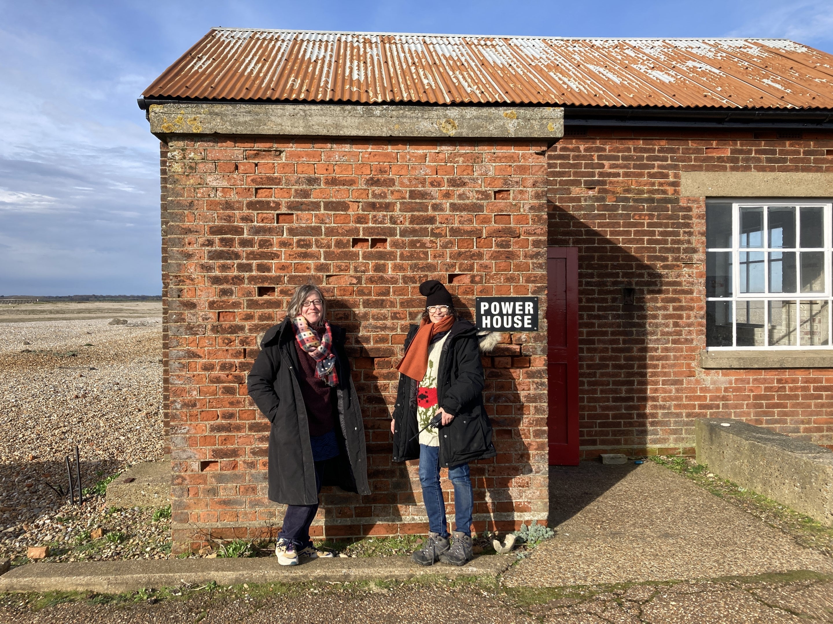 Researchers Dr Jane Watt and Dr SE Barnet stood outside the Power House at Orford Ness on a sunny day