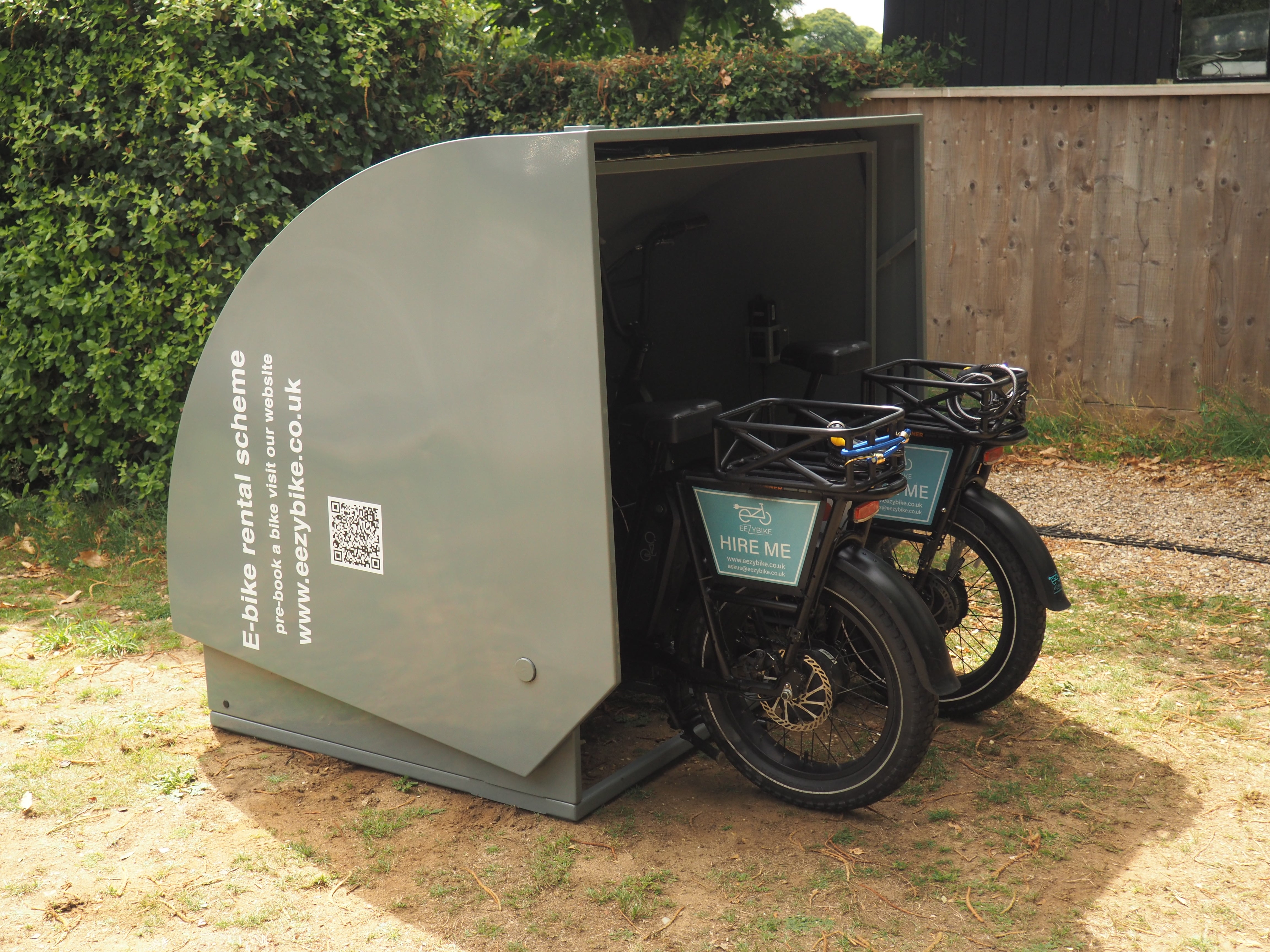 An electric bike charging pod open showing bike tyres on display