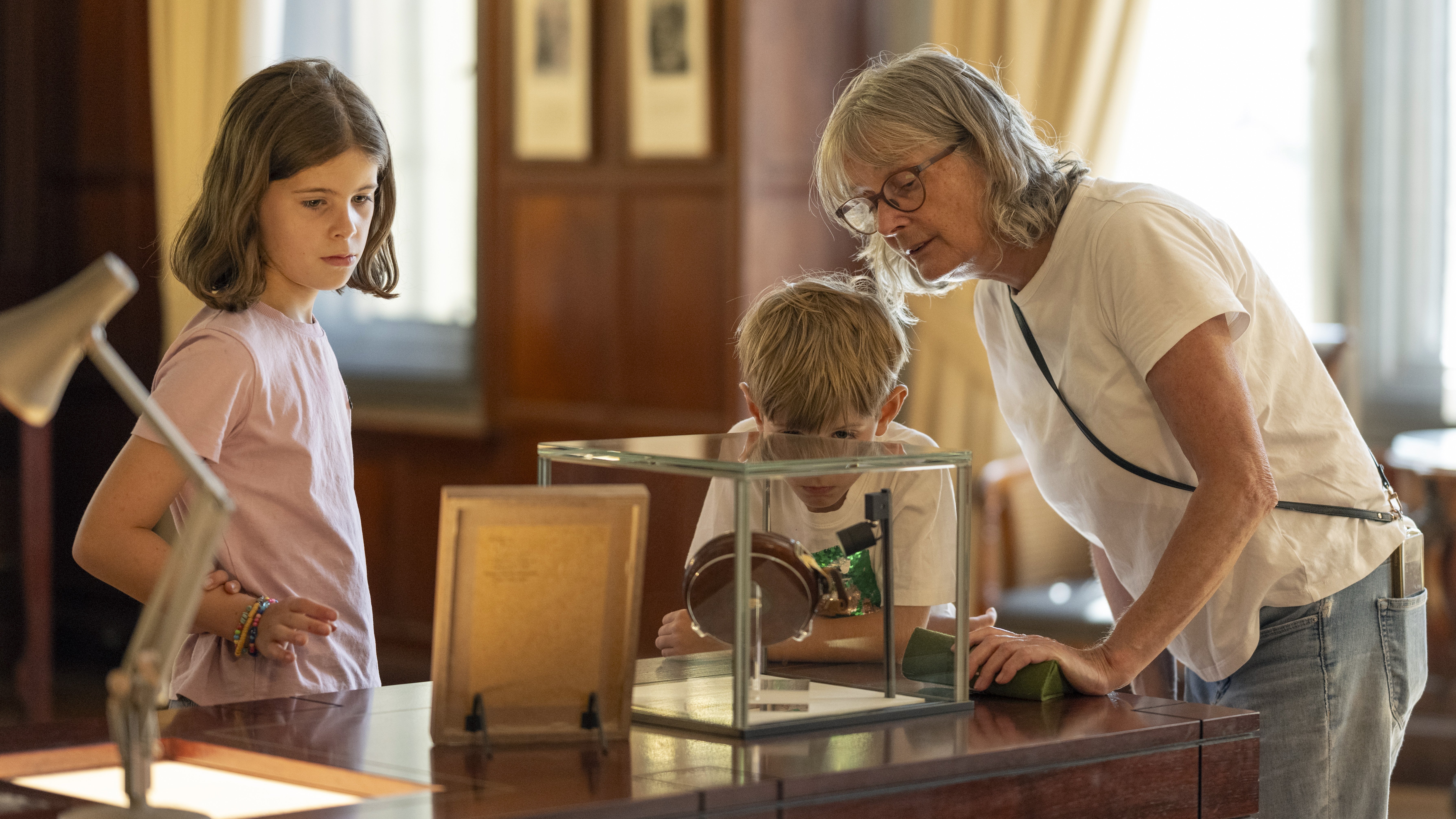 A grandmother and two granddaughters looking at a display about Basil Brown in Tranmer House at Sutton Hoo