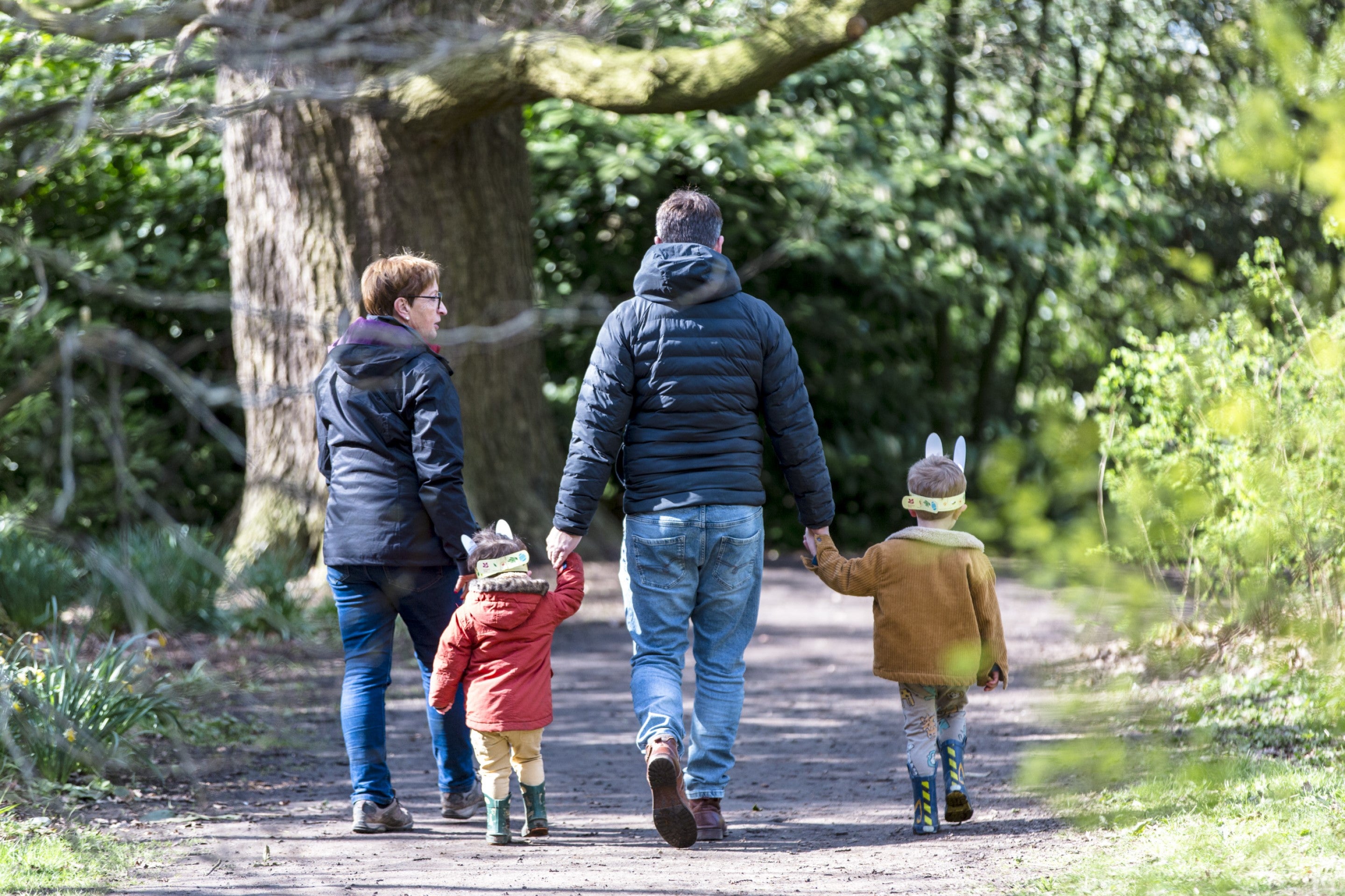 A family holding hands as they walk away from the camera on an Easter trail