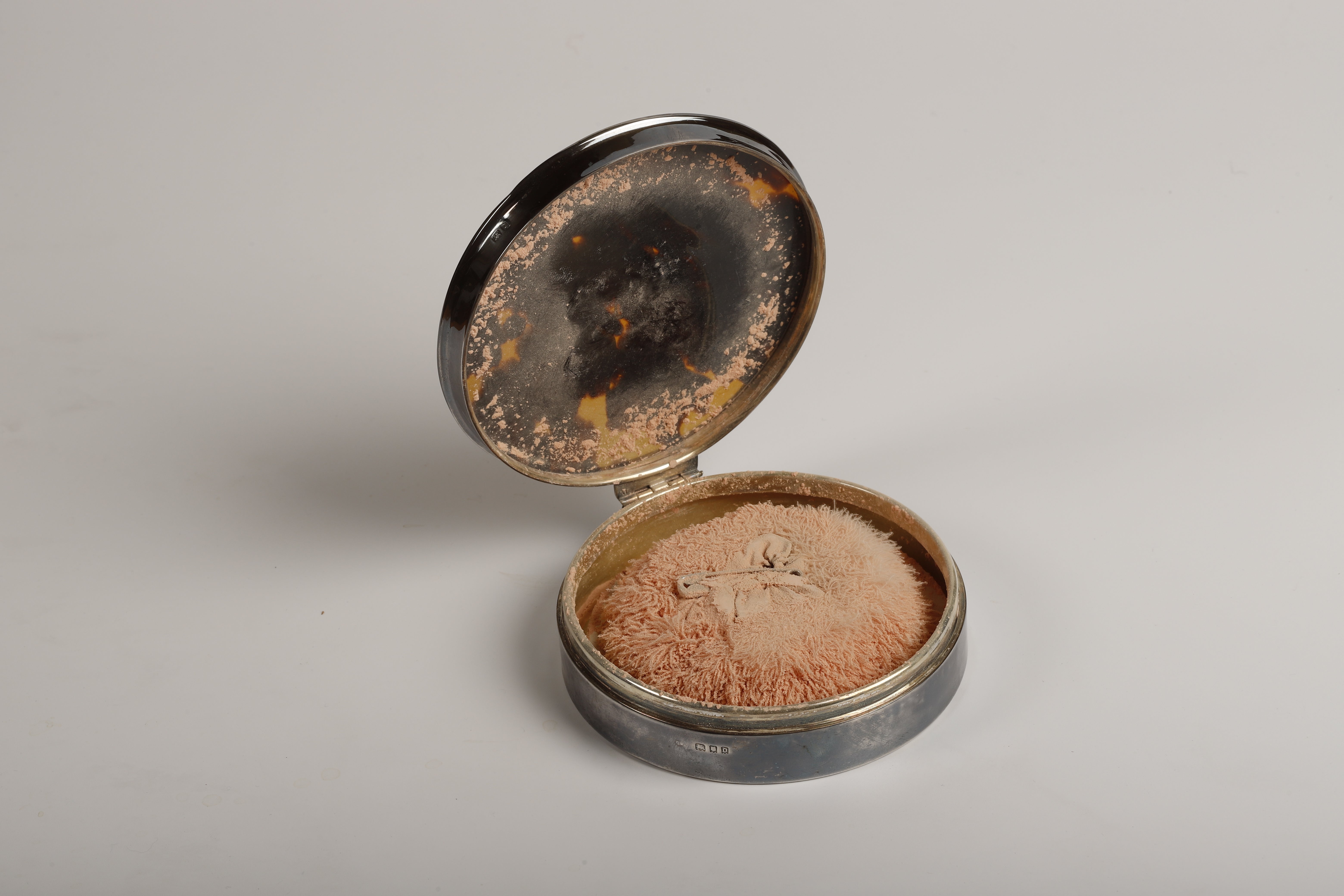A woman's powder compact dating back to the 20th century with a silver case