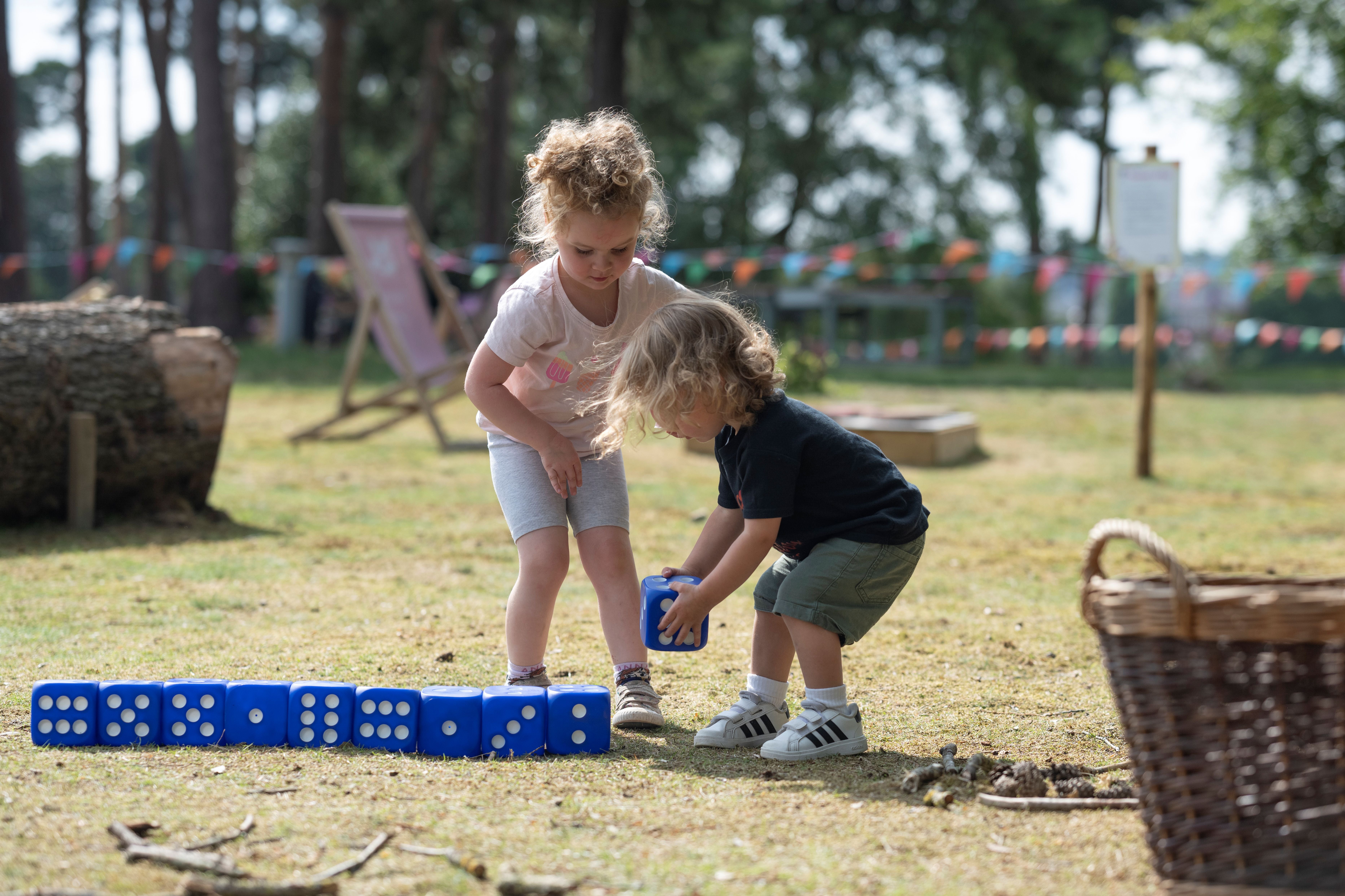 A young boy and girl playing with large dice in the sunshine