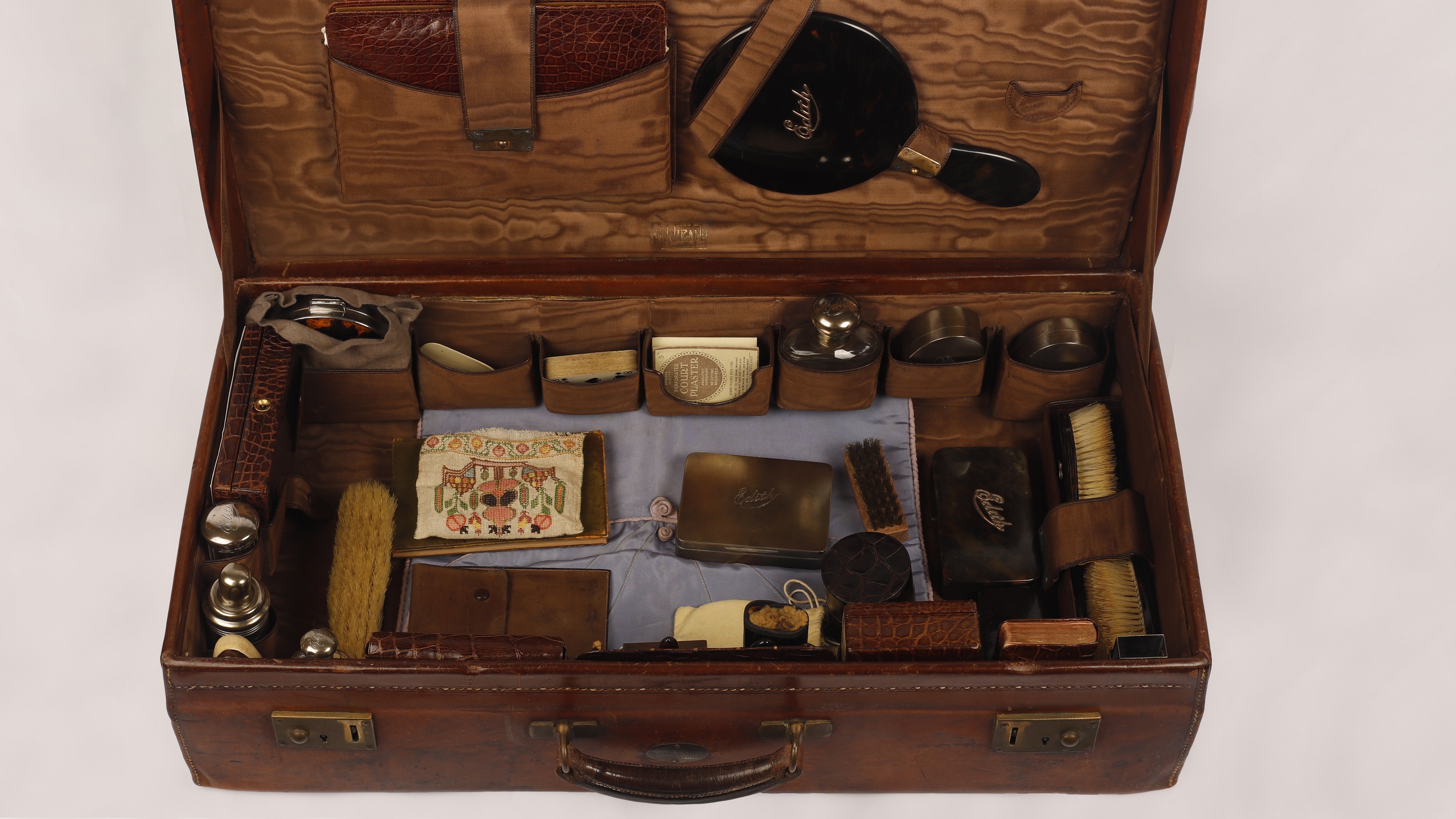 A 20th century leather travel case open with over 100 items including vanity case, sewing kit and first aid kit on display