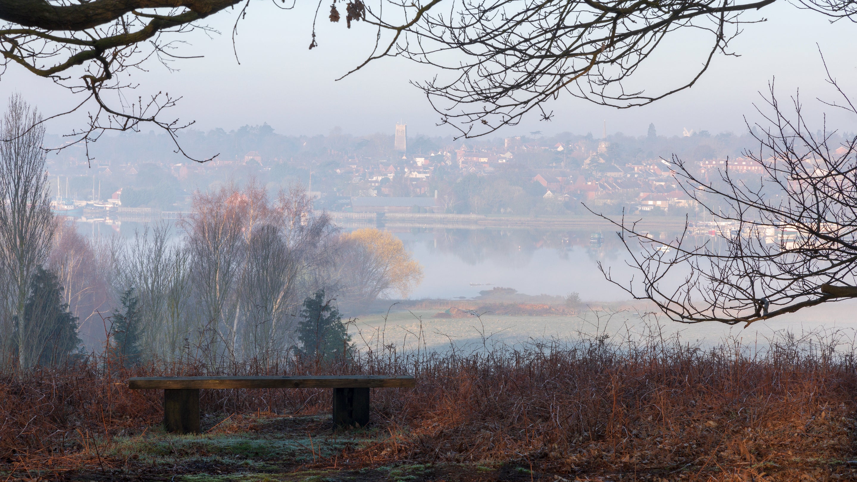 A misty view of the river Deben from Sutton Hoo with bench in the foreground