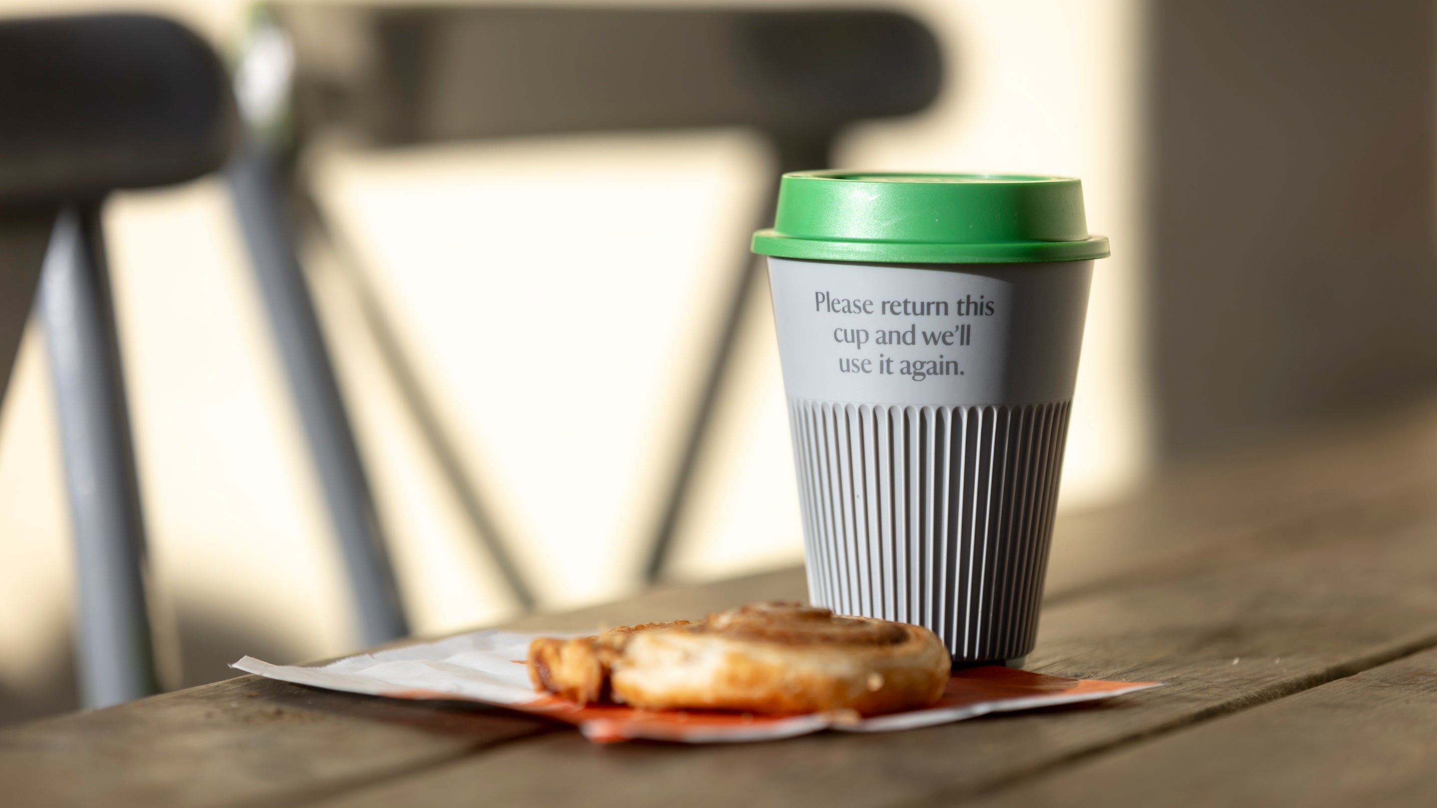 Returnable cup and a pastry on a napkin on a table outside the Box Hill cafe
