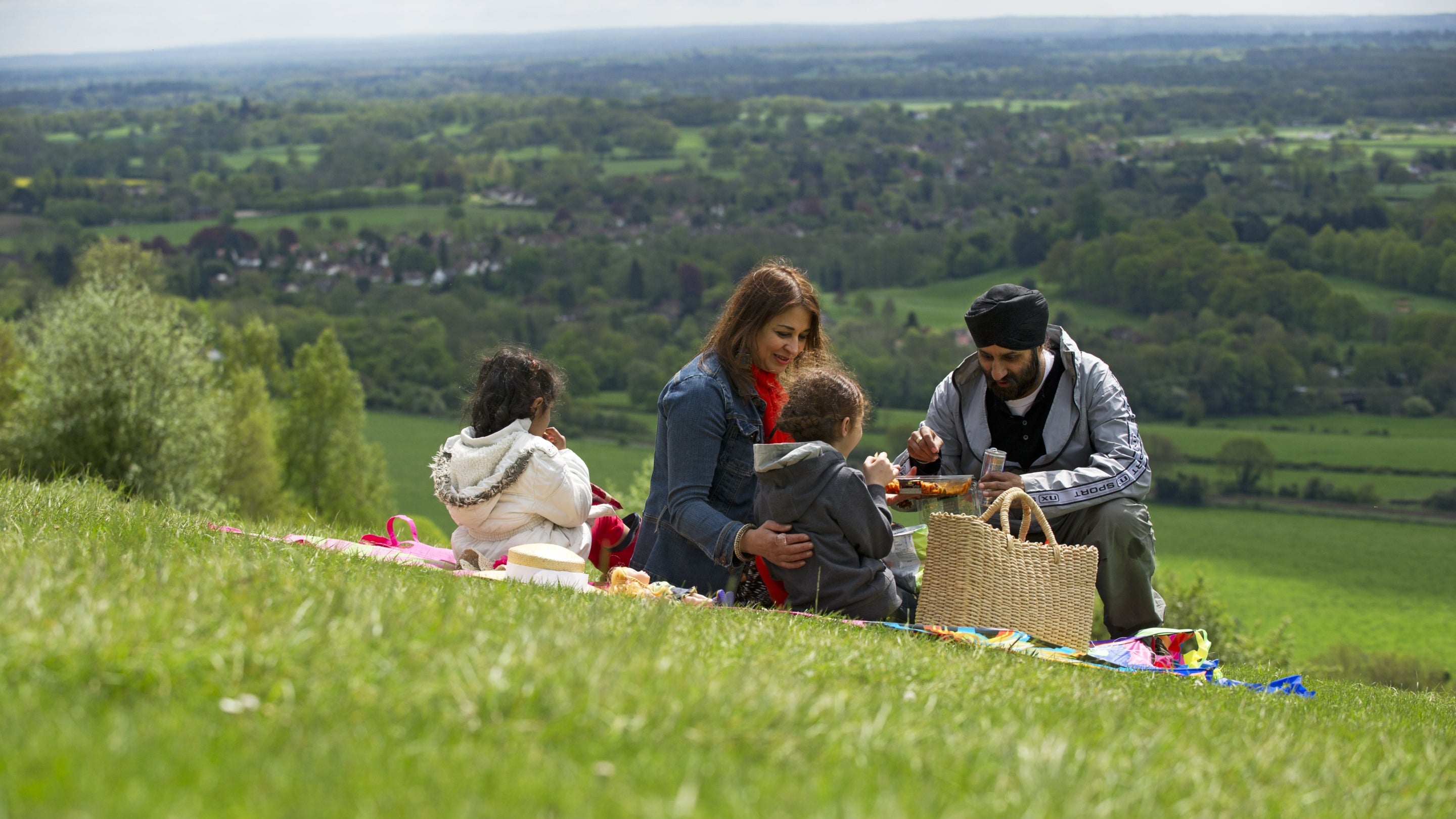 A family enjoying a picnic near the top of Box Hill, with a view of the downs in the background