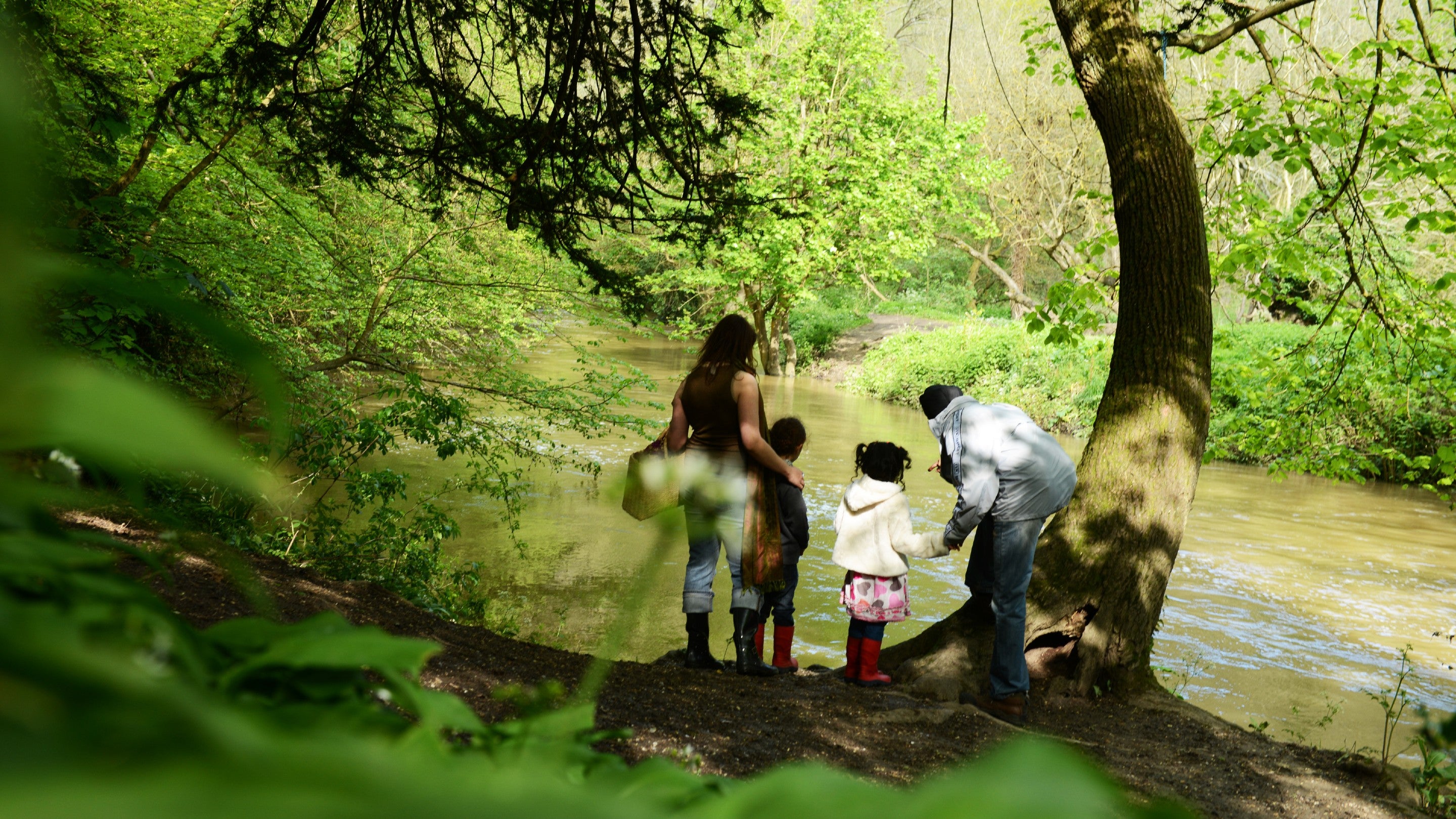 A family standing on the bank and looking across the River Mole at Box Hill, Surrey