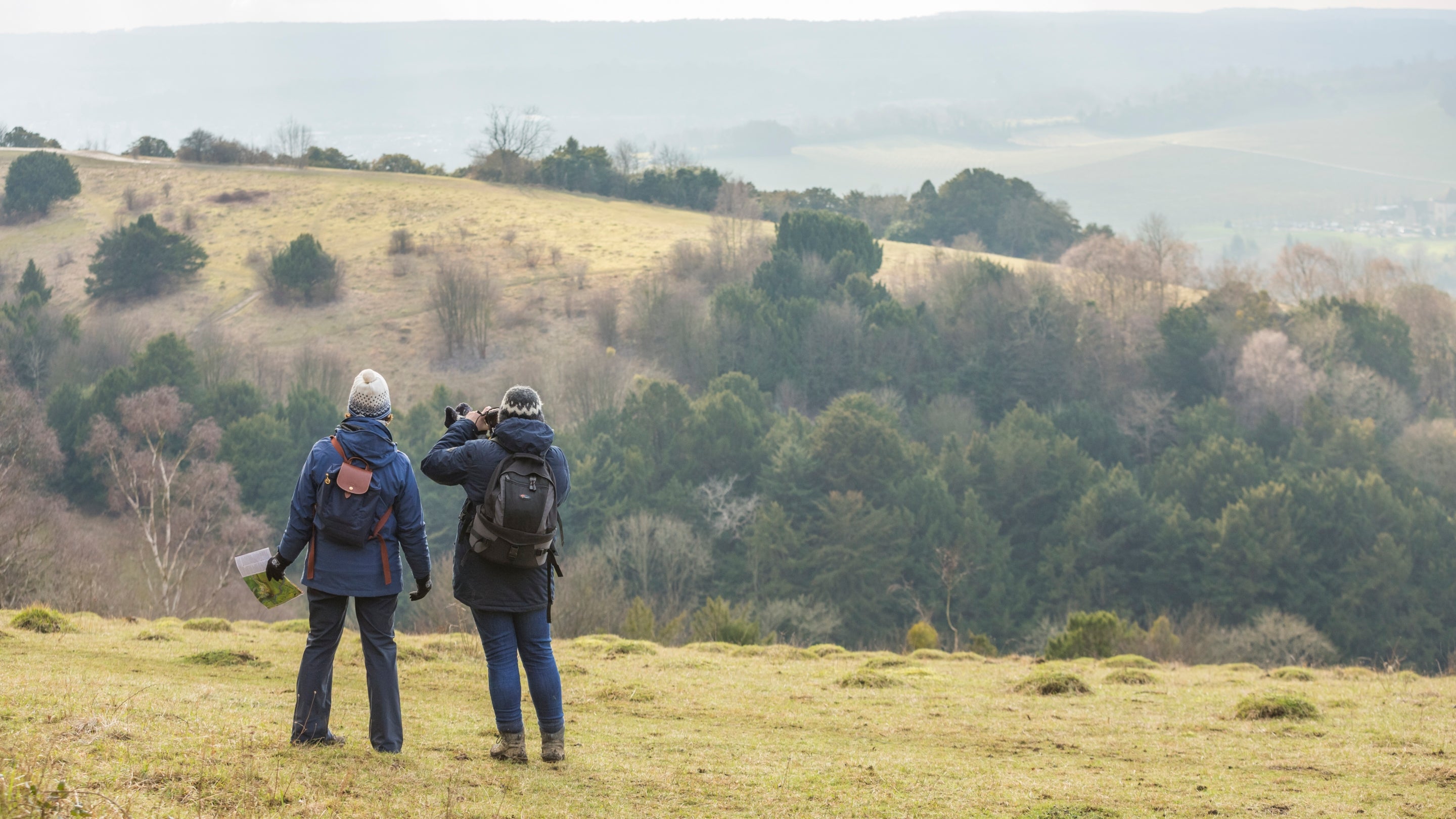 Two women walkers, dressed in winter clothing, admiring the view at Box Hill