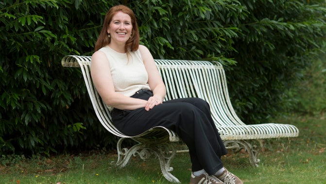 Head of School at Clandon C of E School Hannah Dawe sitting on a bench in the  garden at Clandon Park.