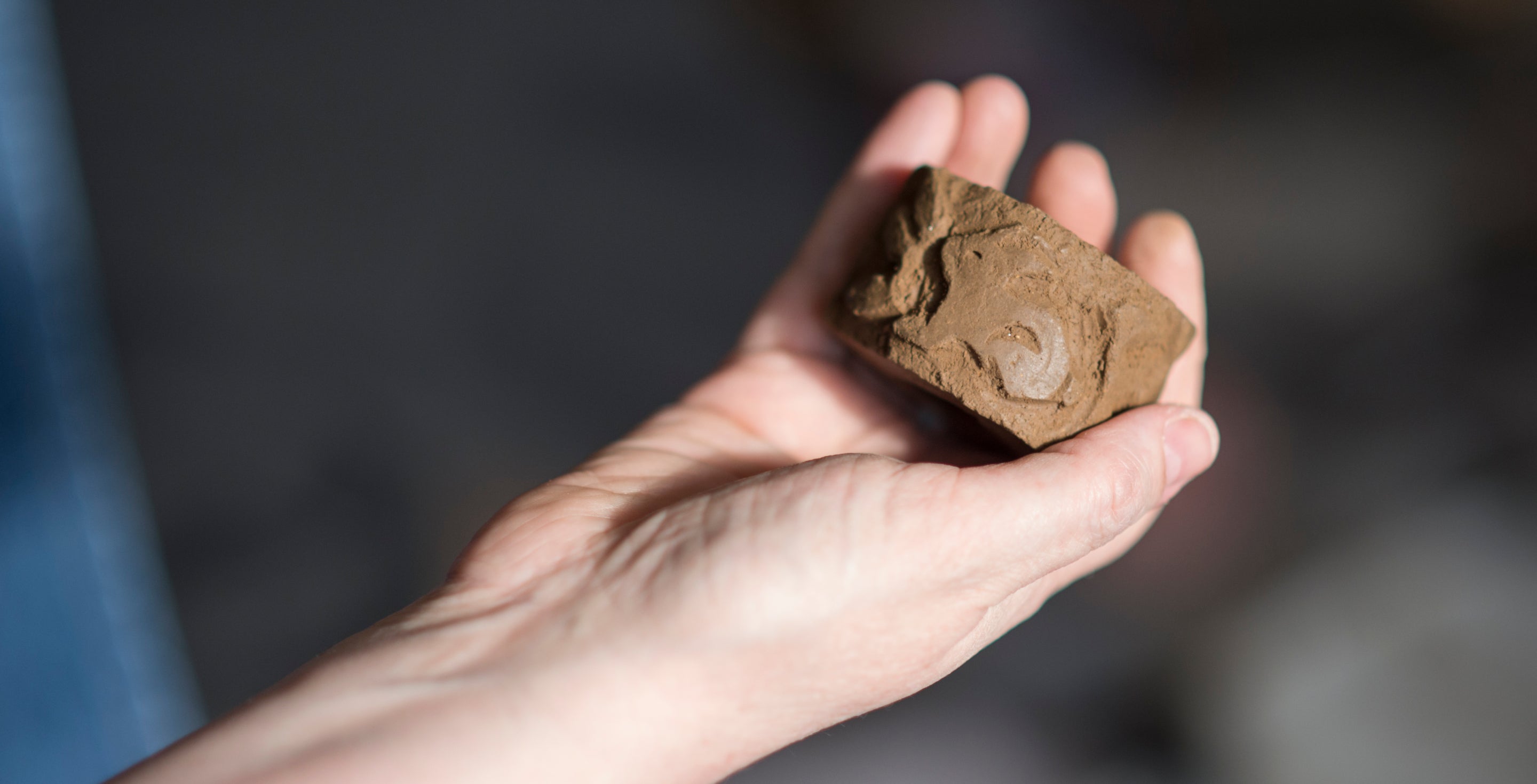 A circular clay chimney roulette with a rabbit pattern held in an outstretched hand