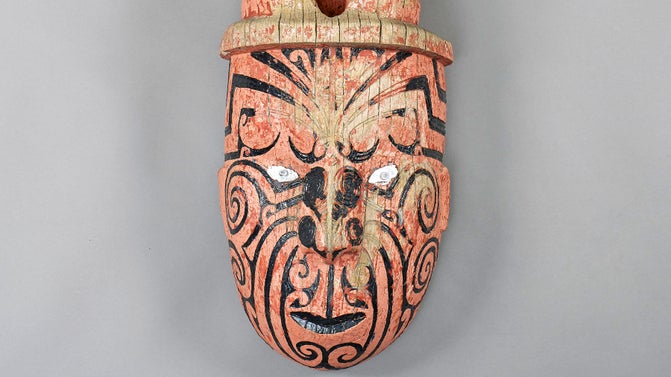 A Māori whakairo (carving) of a face painted red and black from the wharenui (meeting house) Hinemihi