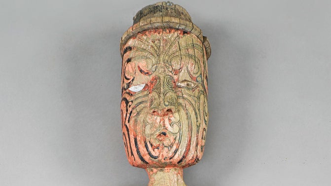 A Maori carving (whakairo) of a face painted red