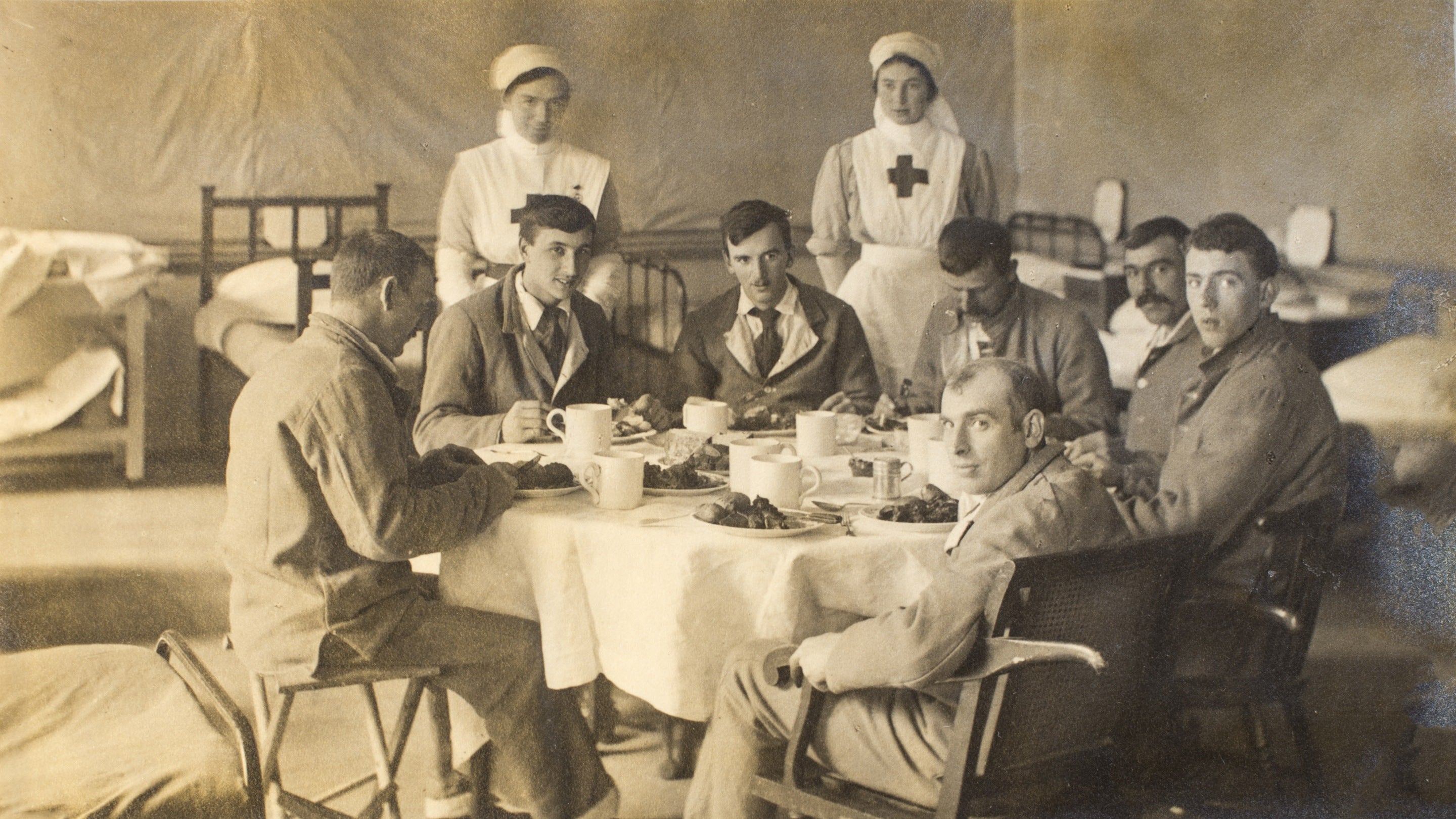 A black and white photograph of seven patients dining in the ward with two nurses at Clandon Park, Surrey during the First World War