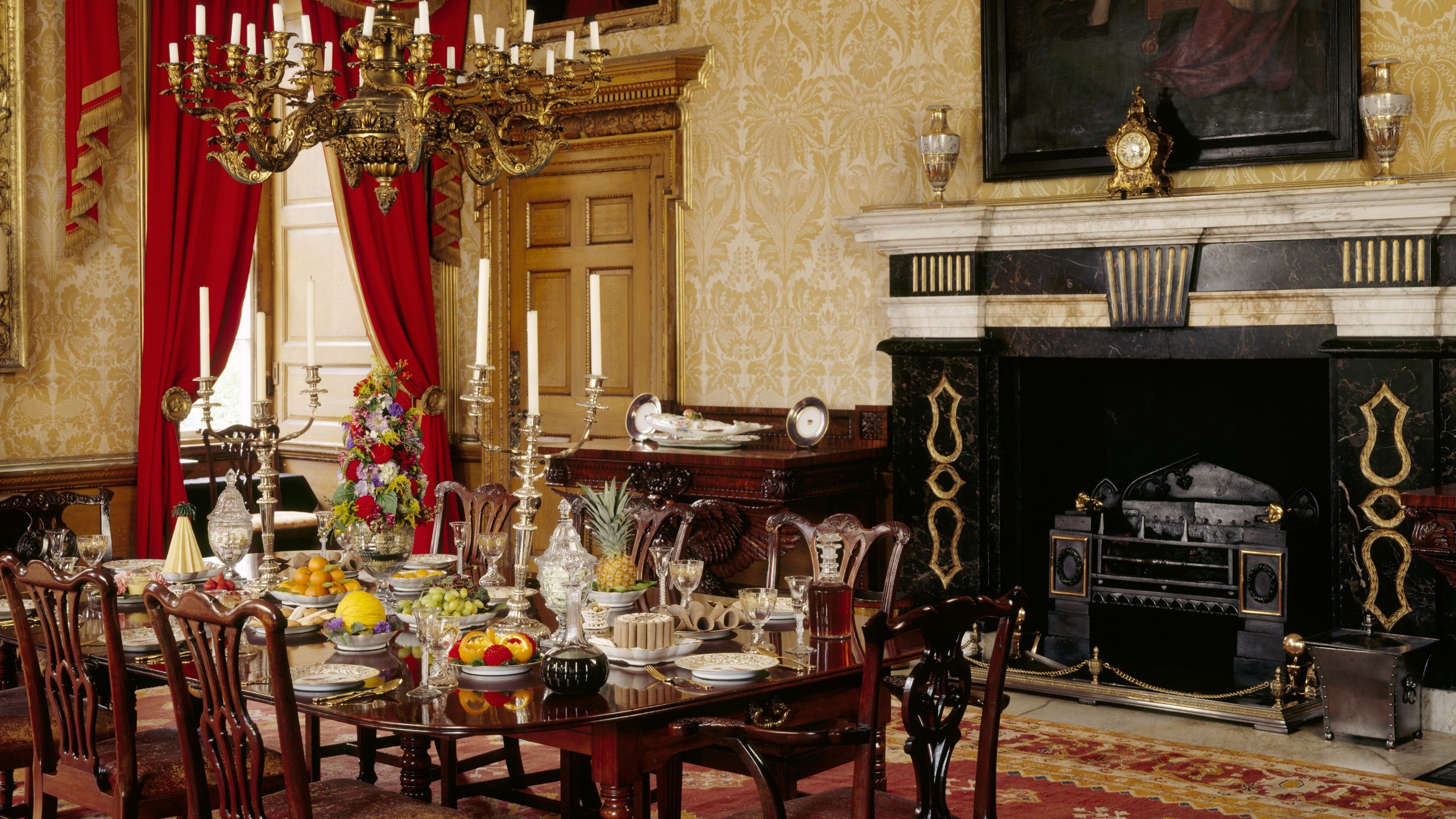Inside the Speakers' Parlour with portraits on the wall above a fireplace and a laid dining table at Clandon Park, Surrey
