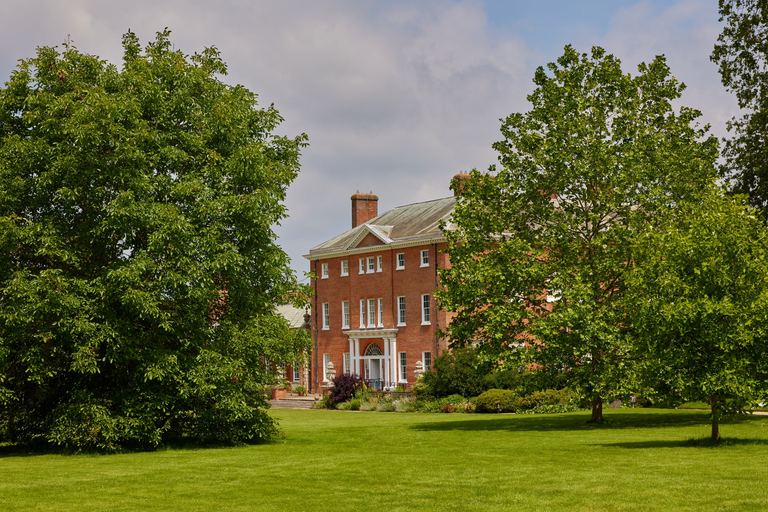 Exterior view of Hatchlands house with a lawn and trees in front of the house