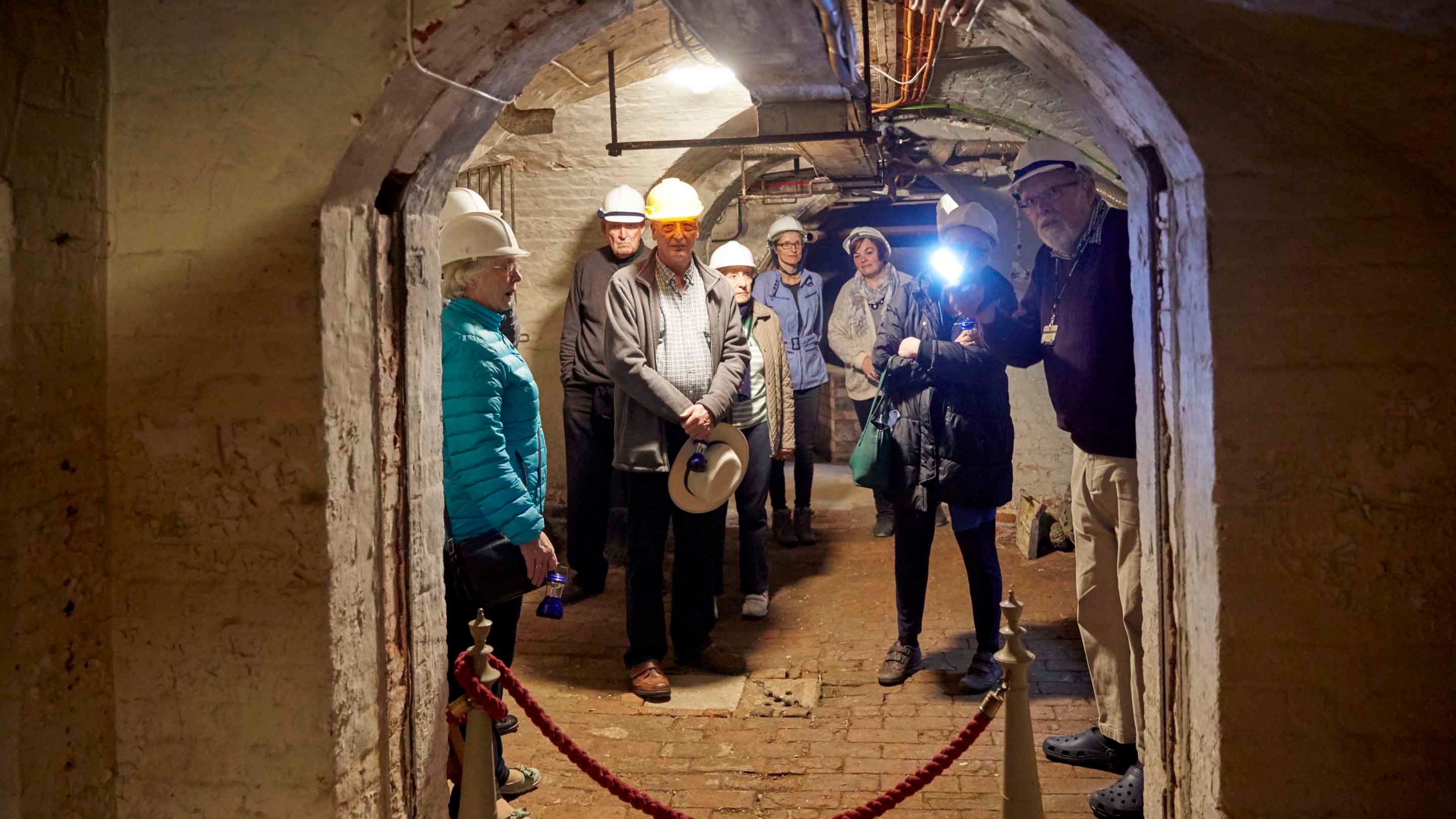 Visitors, wearing hard hats, on a tour of the cellars at Hatchlands Park, Surrey