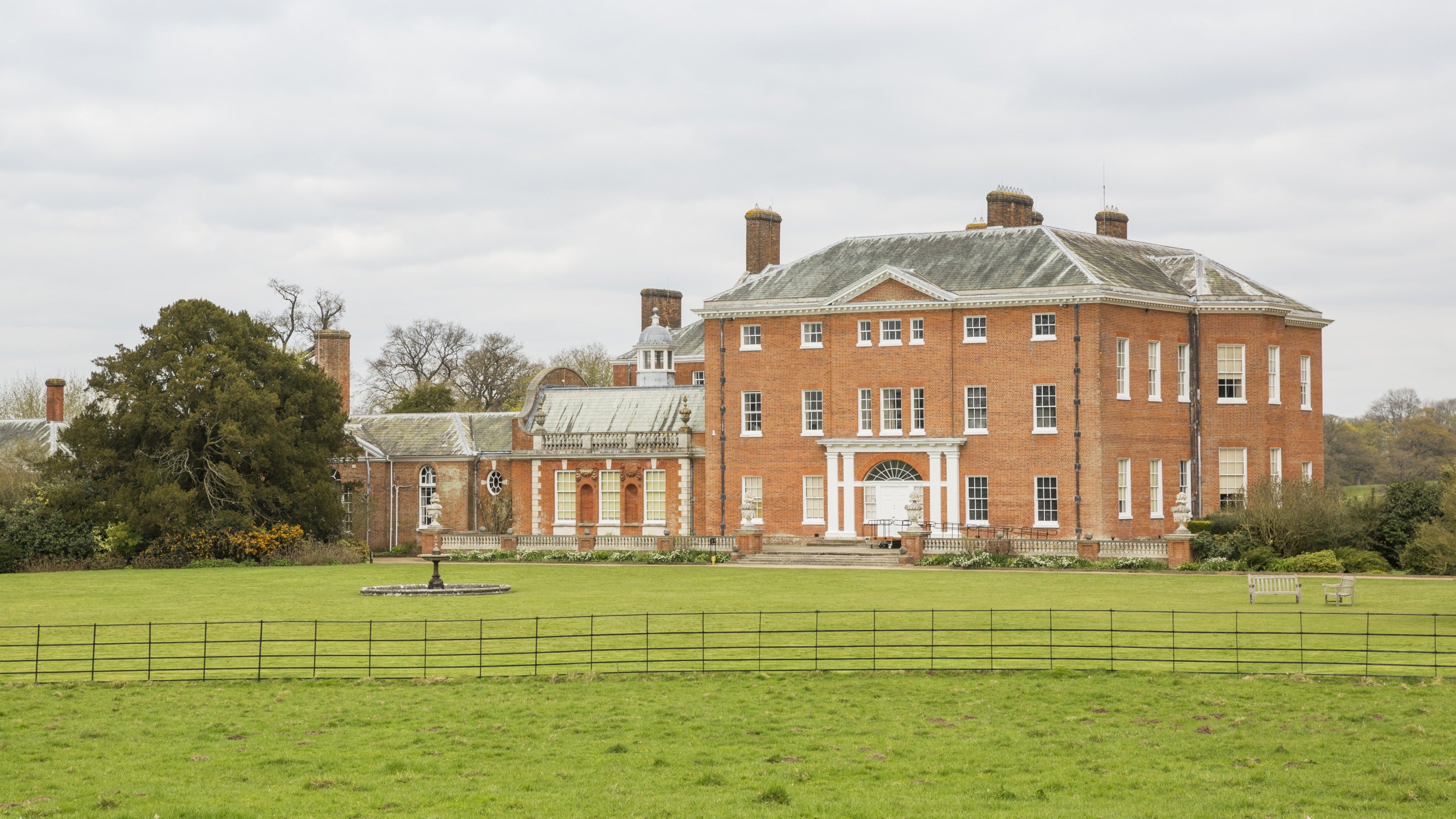 A view across the park to the 18th century, red brick house at Hatchlands Park, Surrey