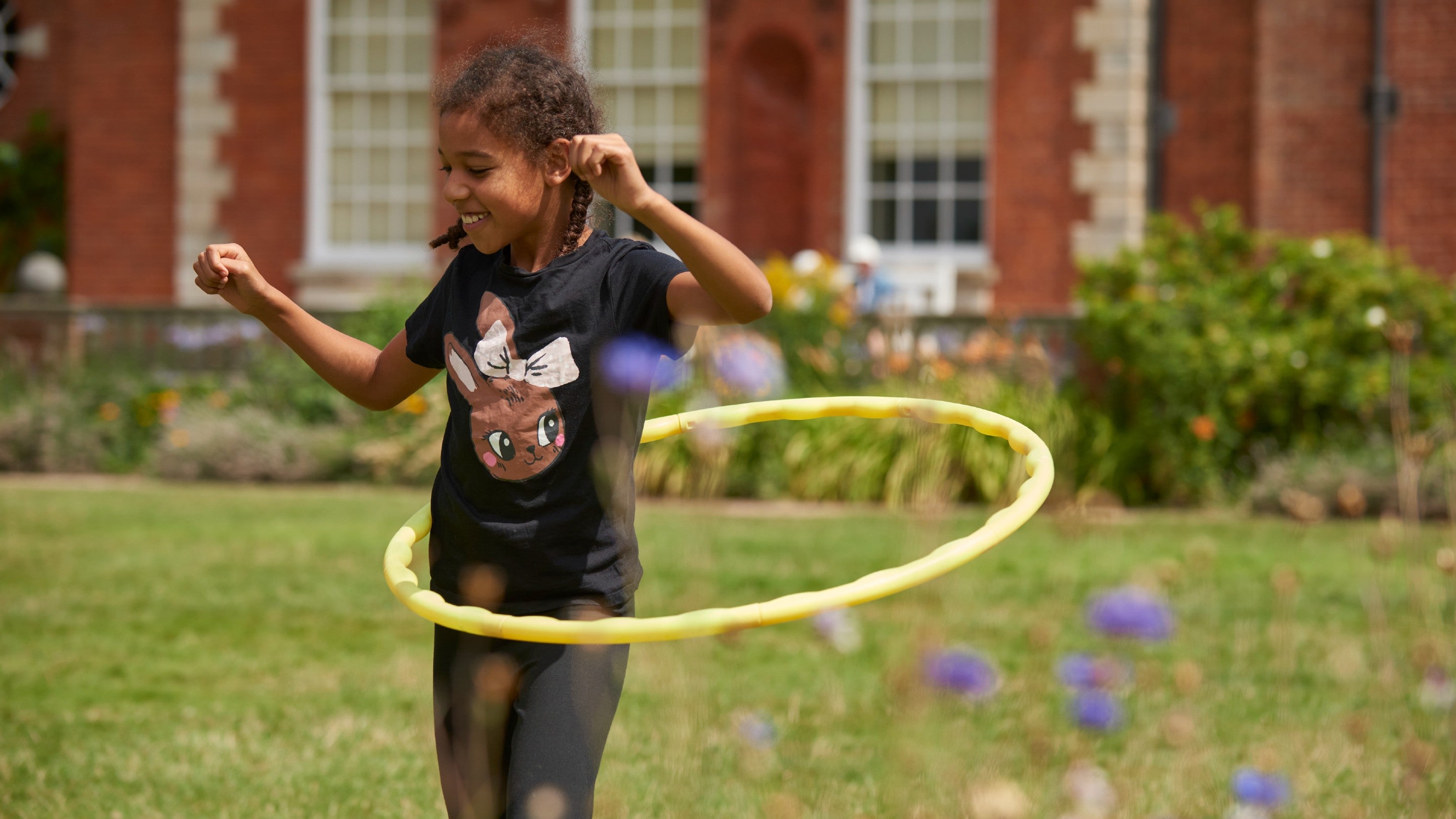 Girl hula hooping on the lawn at Hatchlands Park