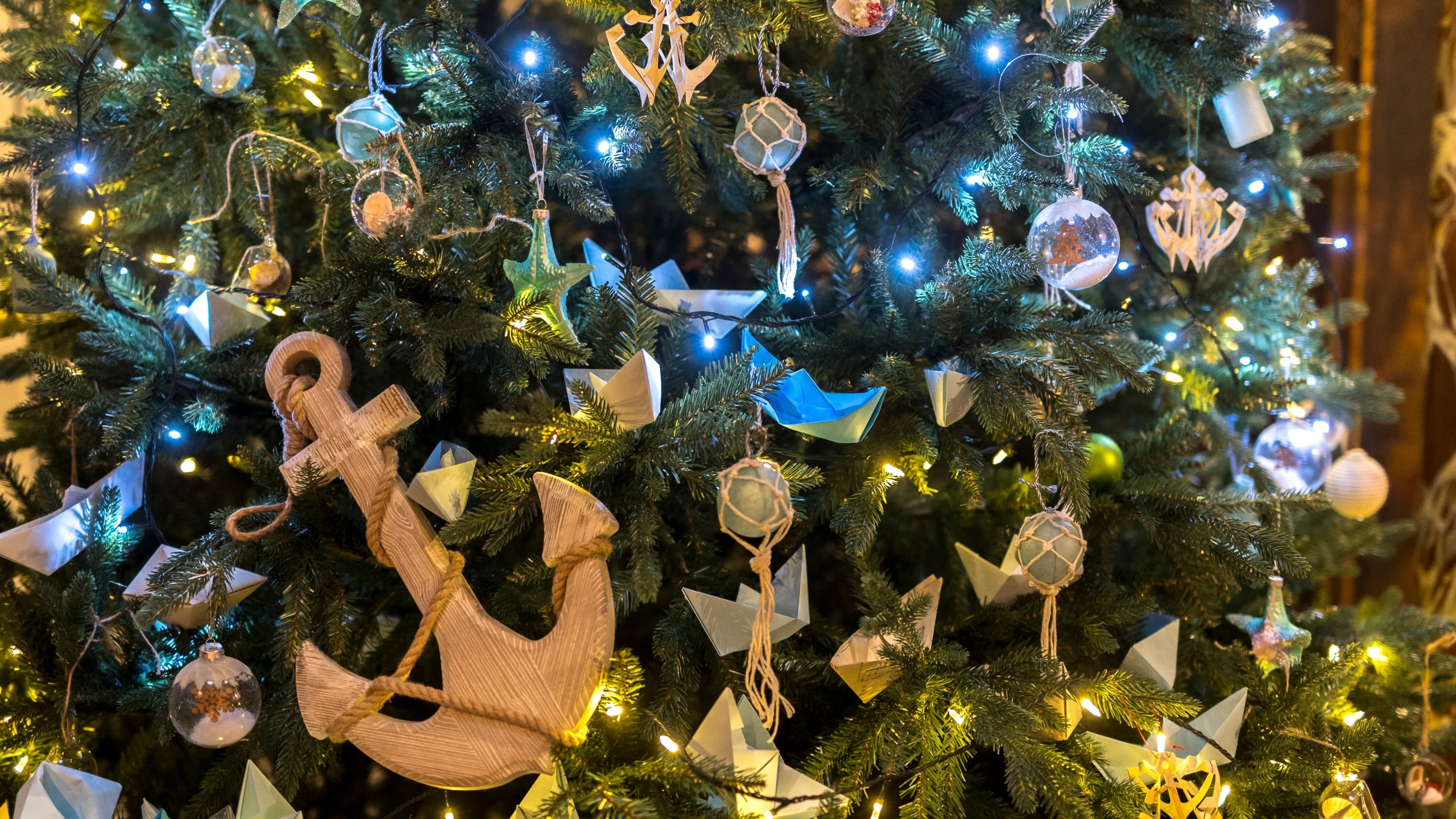 Close up of Christmas tree decorated in a nautical theme with a large wooden anchor in the foreground