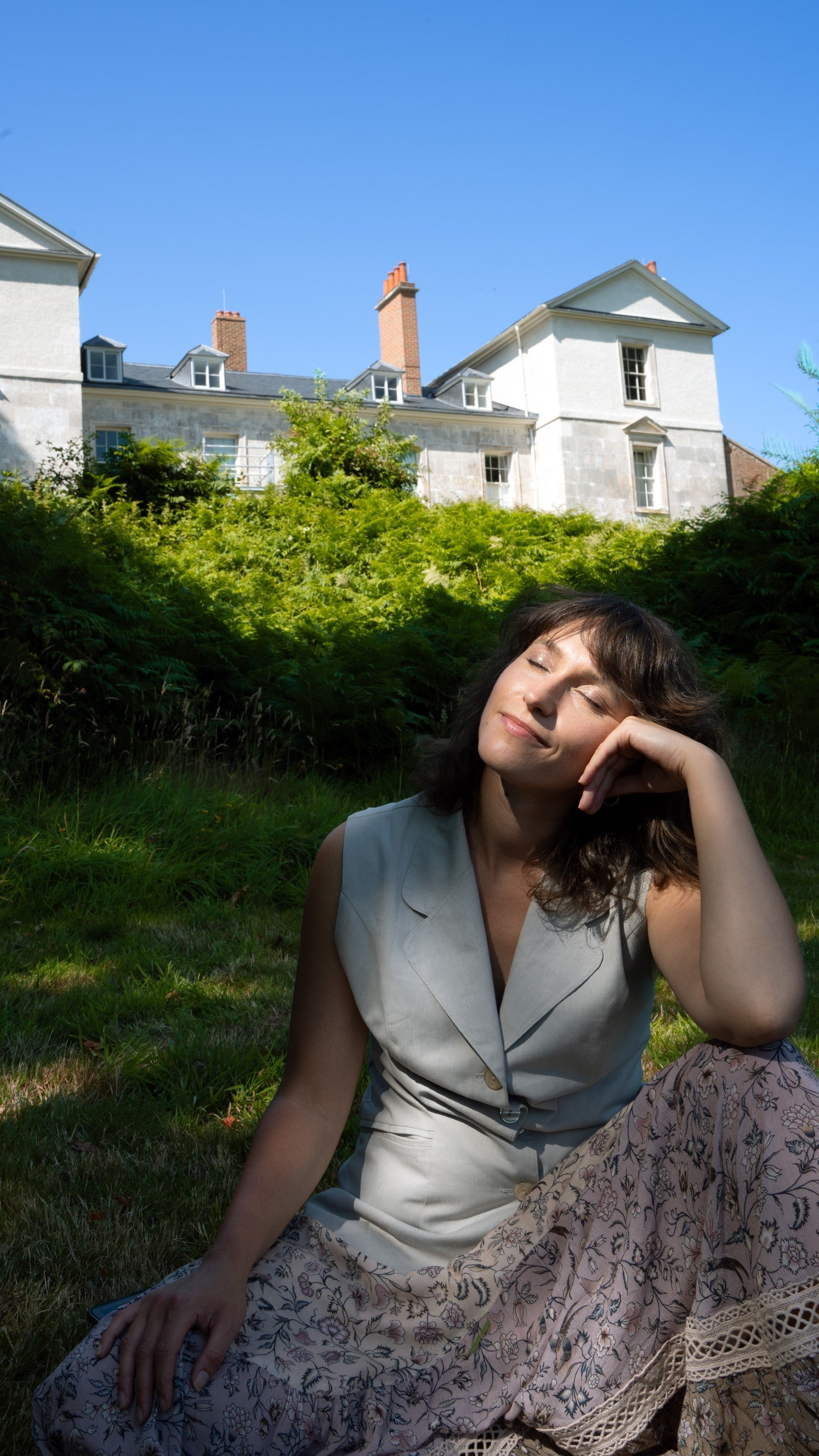 Woman sitting in the sun, with her eyes closed outside Leith Hill Place.