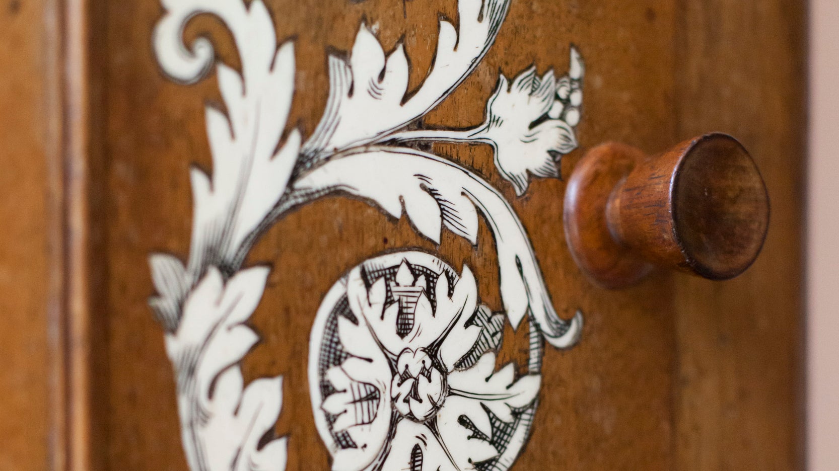 A white floral design is shown on an oak cupboard