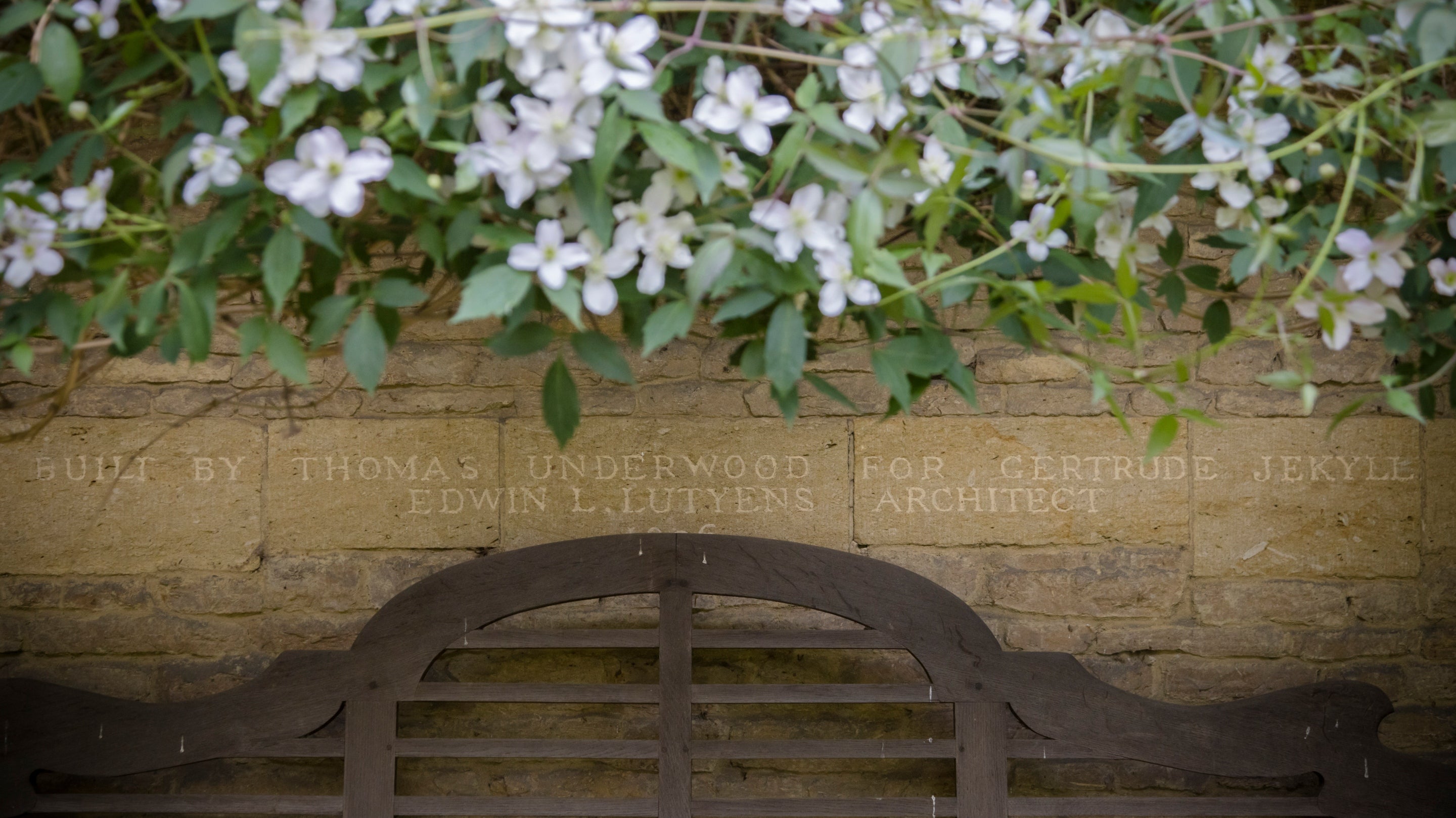 Detail view of an inscription in a stone wall at Munstead Wood.  The inscription reads "Built by Thomas Underwood for Gertrude Jekyll. Edwin L. Lutyens Architect. 1896"