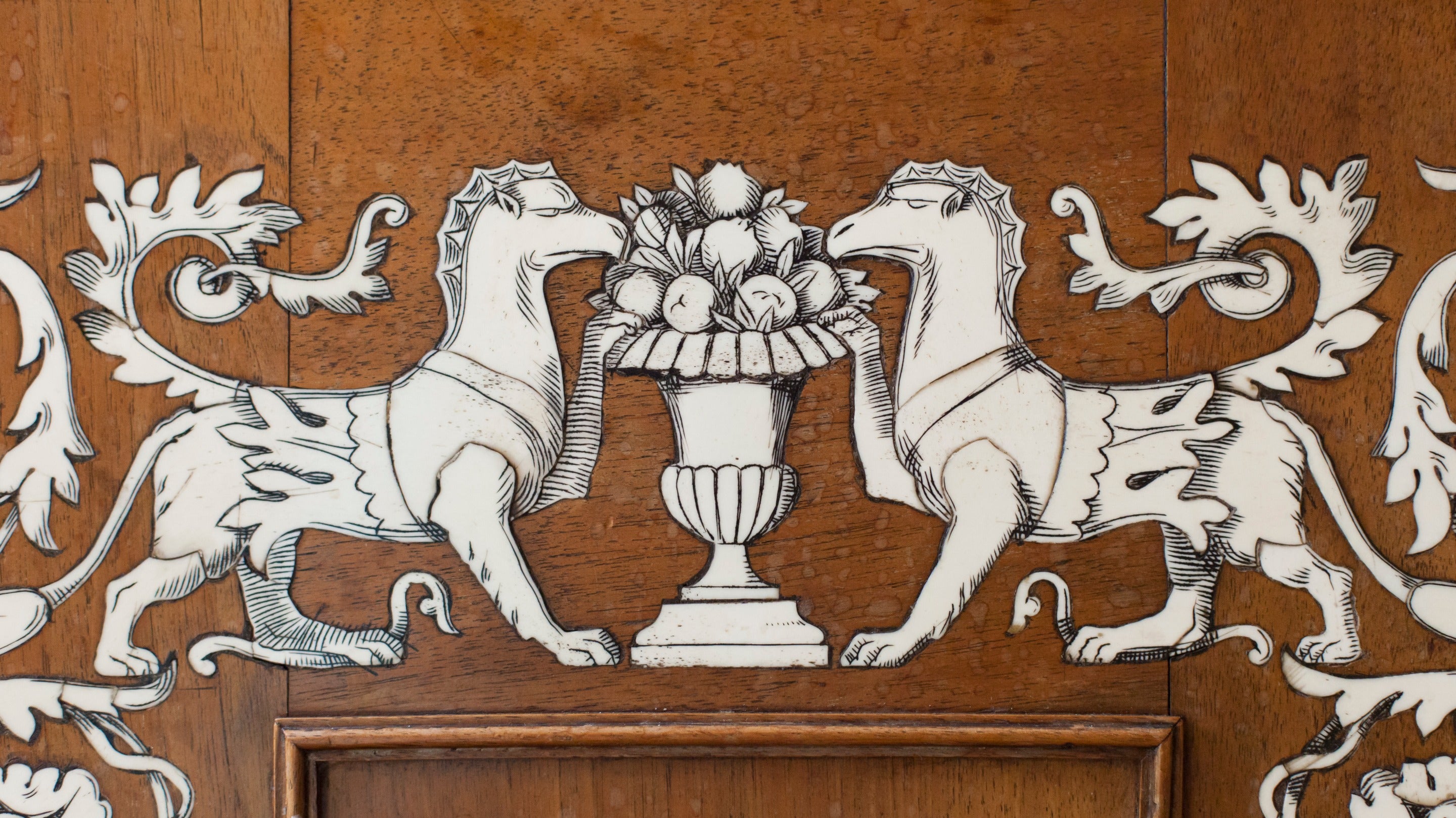 White bone figures of two dogs and an urn of fruits are inlayed in an oak cupboard door. Munstead Wood Surrey