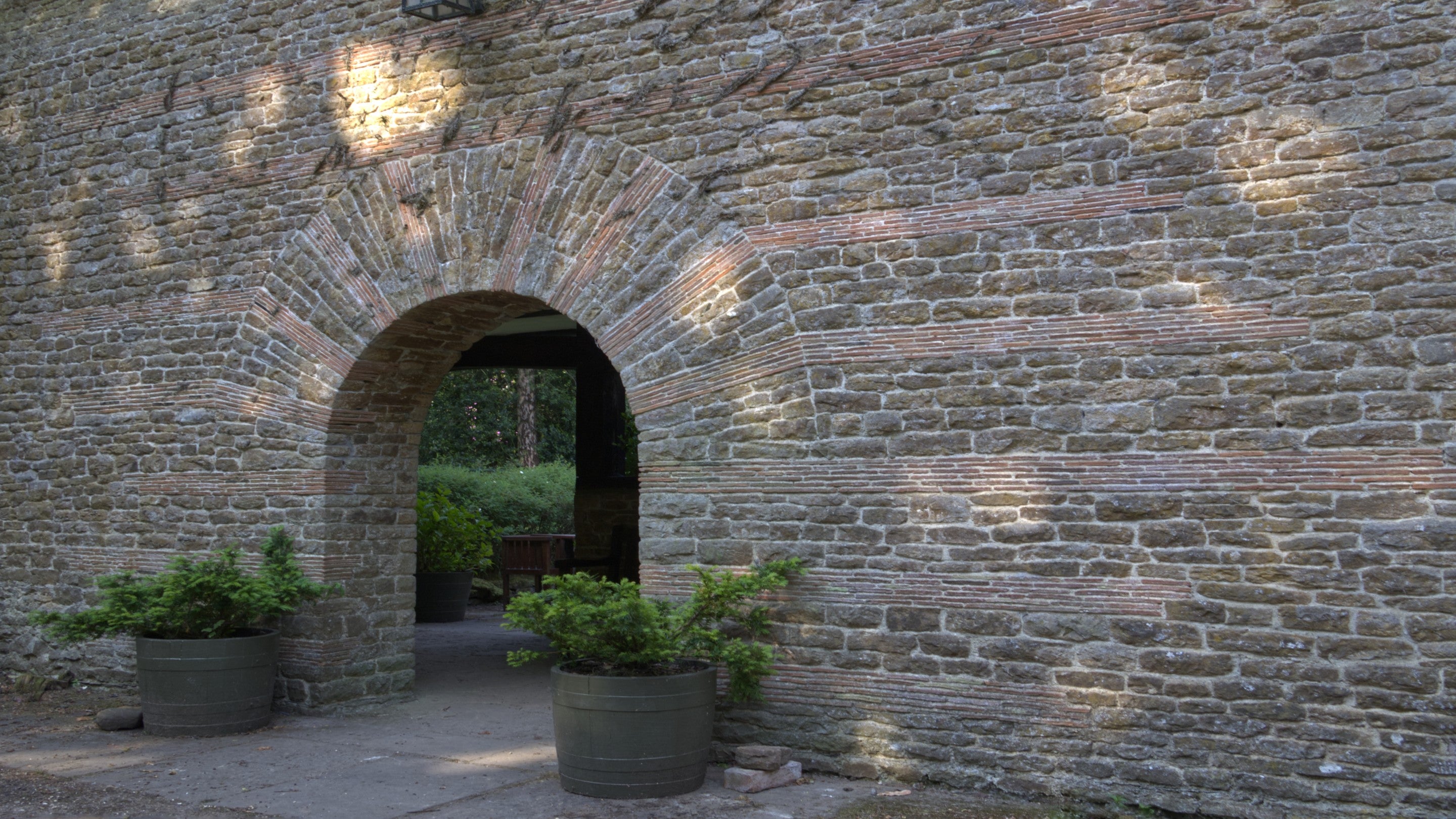 A large round entrance way with a sundial brick design at the top shows a route through to a corridor and garden.