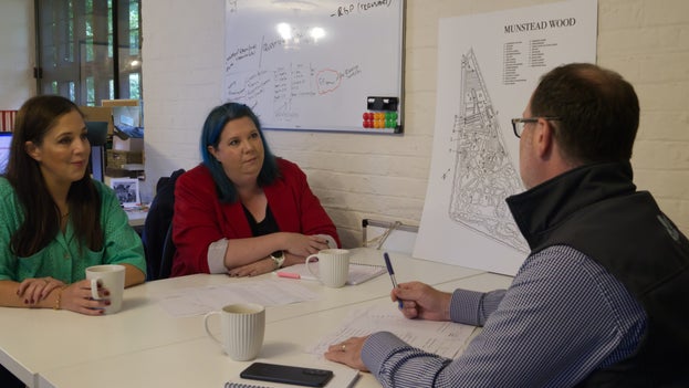 Three people in discussion around a table in an office