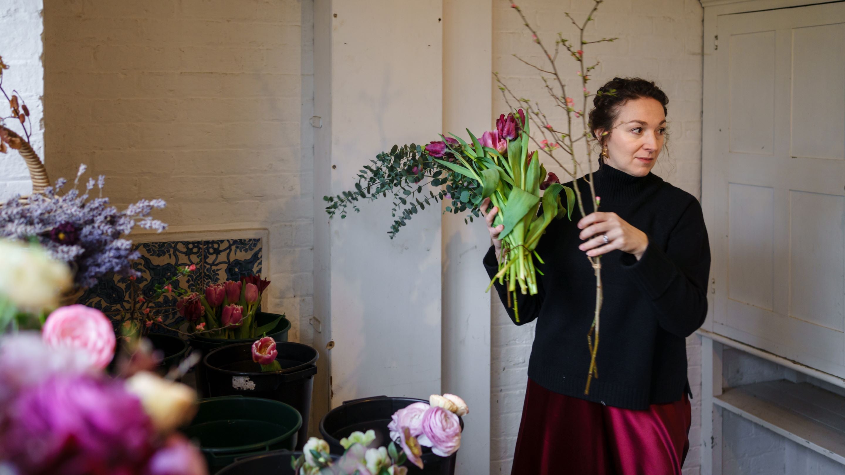 Leanne Smith holds a branch of foliage in the flower shop of Munstead Wood