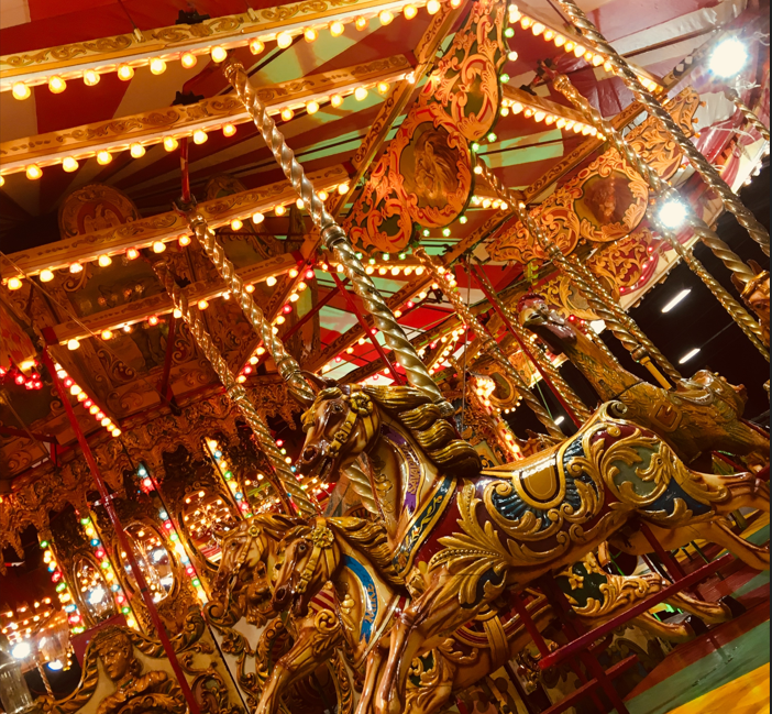 Close up shot of horses on a vintage carousel ride with bright lights.