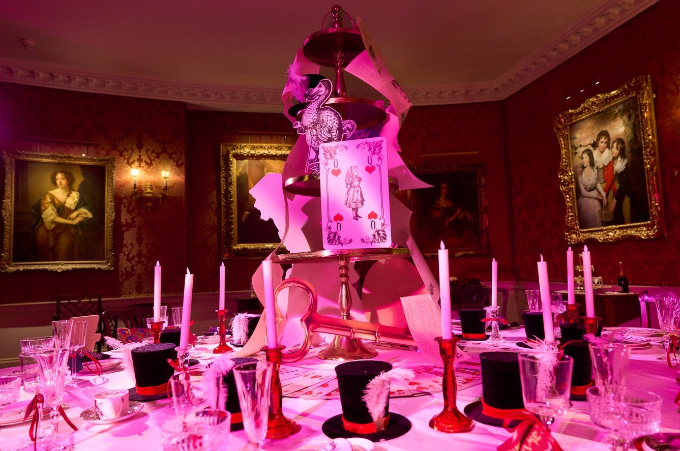 Round dining room table at Polesden Lacey dressed for Christmas with candles, black top hats and playing cards