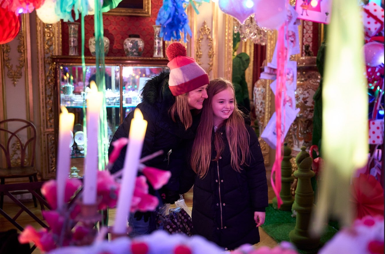 Alice's Christmas in Wonderland at Polesden Lacey 2025 - a woman and girl smile as they admire the Christmas decorations around them
