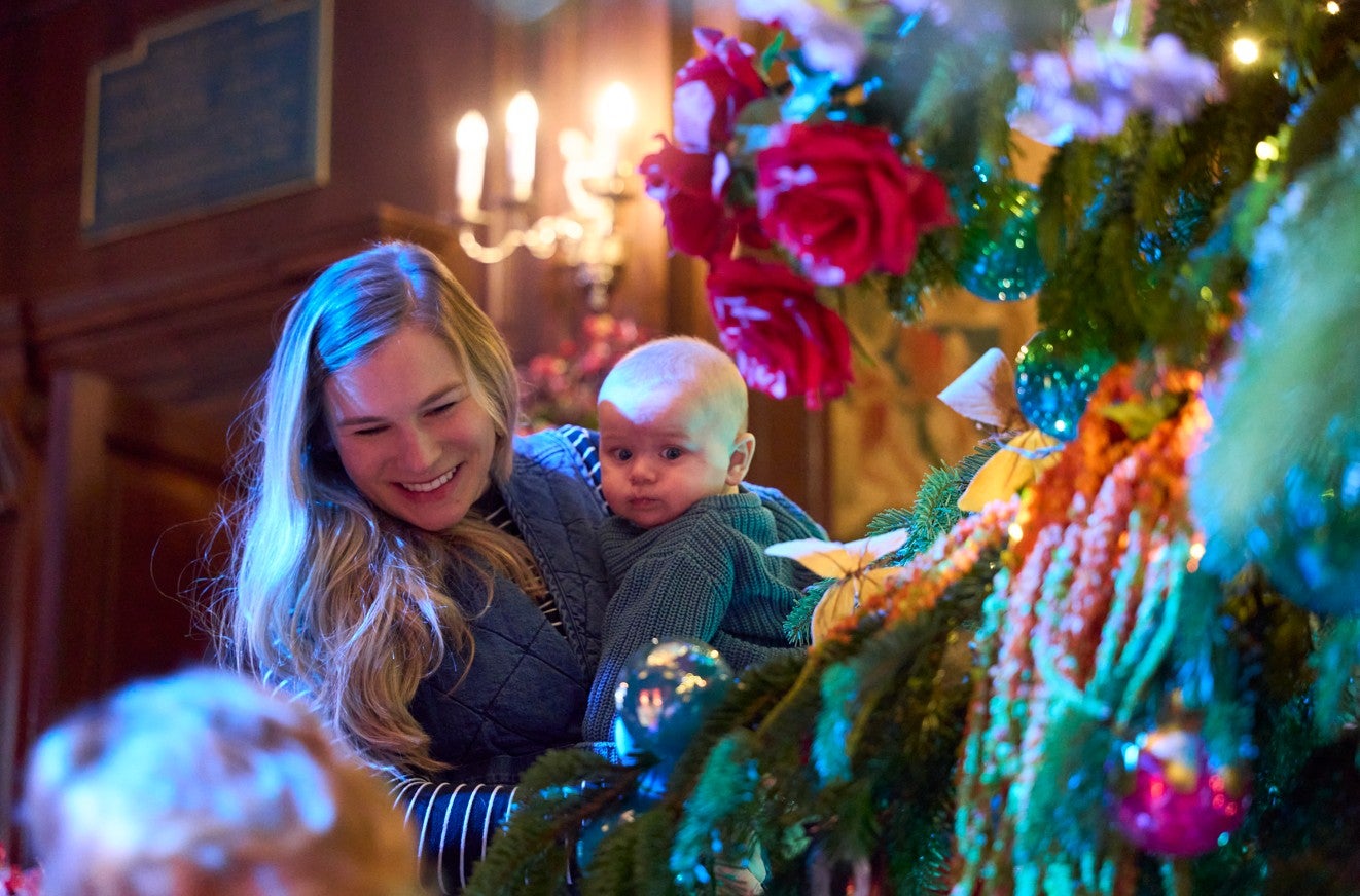 Alice's Christmas in Wonderland at Polesden Lacey 2025 - a mother holding a young baby smiles at a decorated  Christmas tree