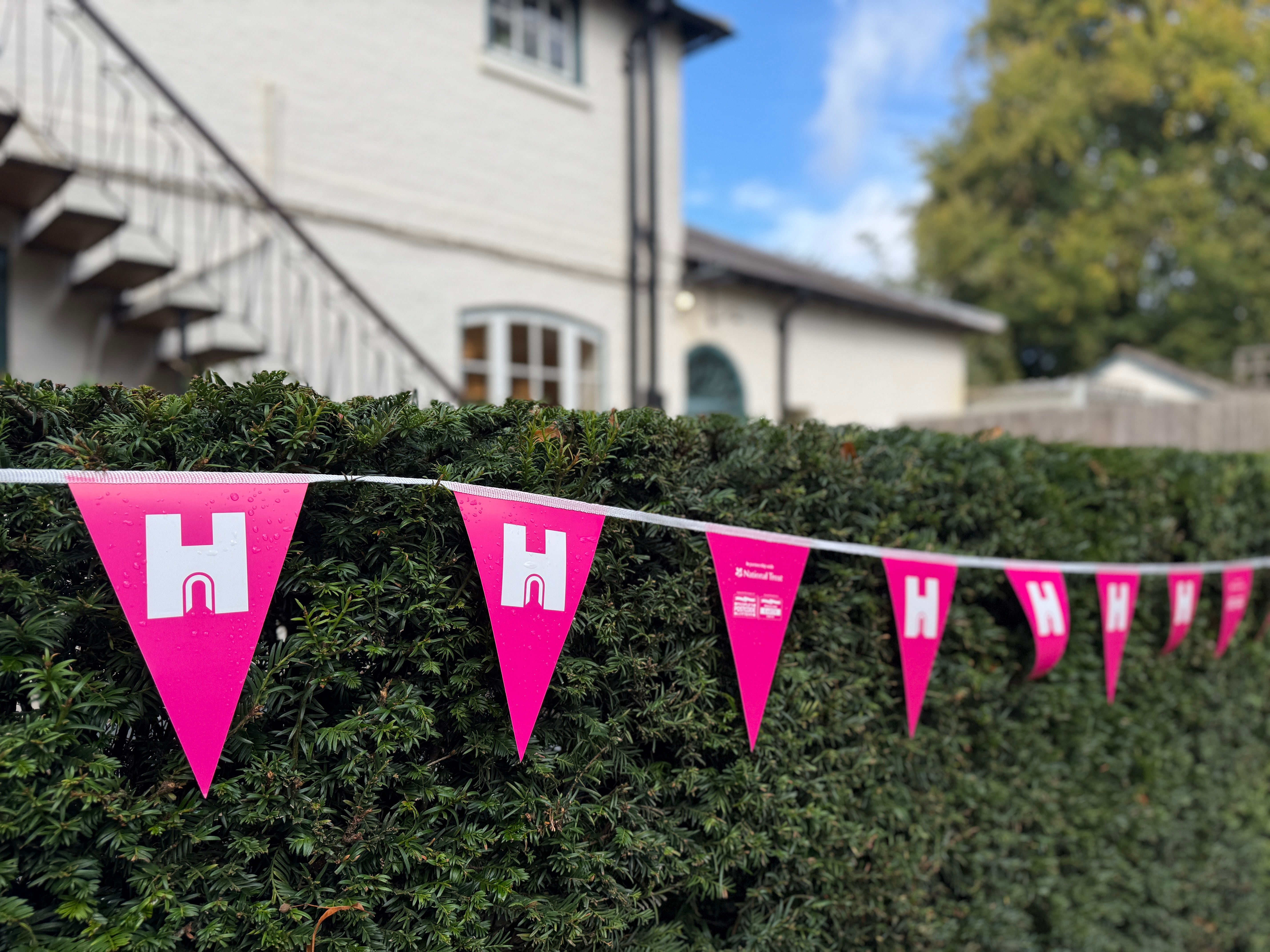 Pink and white Heritage Open Day bunting along a hedge at Polesden Lacey