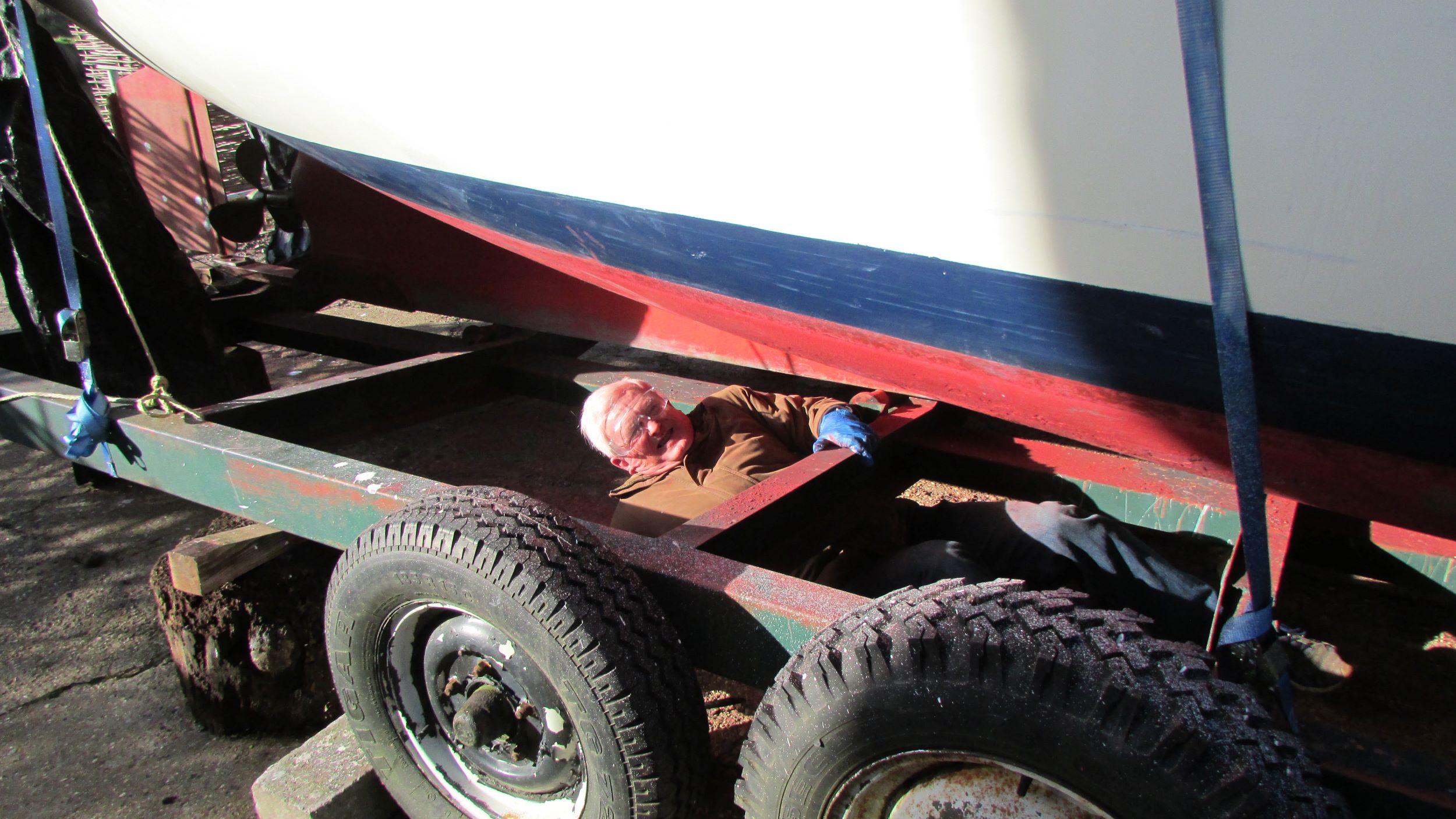 Volunteer skipper lying down, scrubbing the bottom of Dapdune Belle