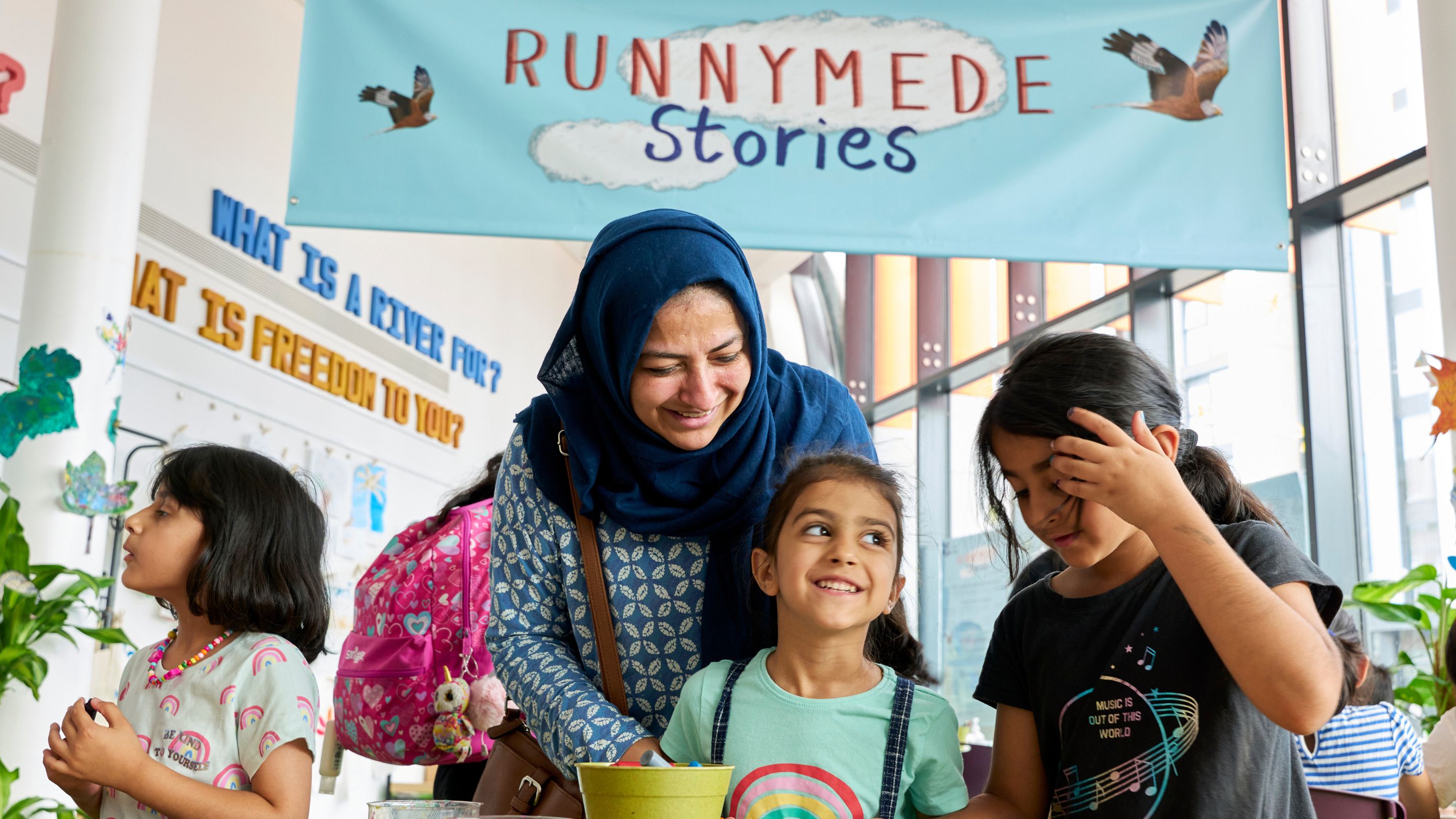 Parent and two children enjoying a craft activity at table within a library space.