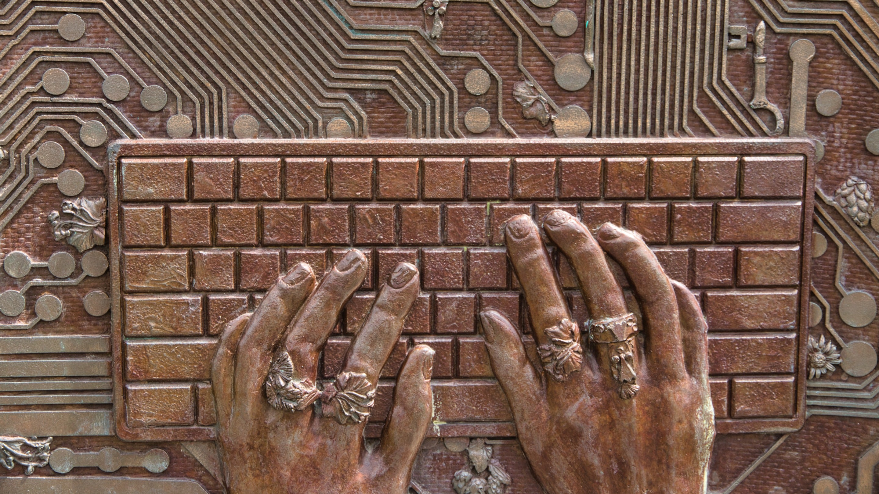 Close-up of chair 8 of The Jurors by Hew Locke, an artwork on display at Runnymede, Surrey: two representations of freedom of speech, public and online, featuring hands typing on a keyboard