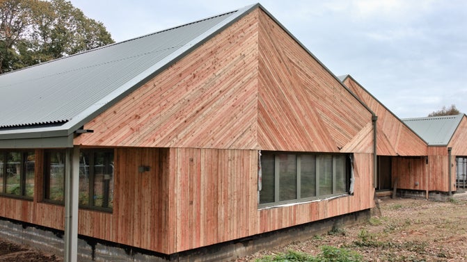 An exterior shot of new building at Winkworth Arboretum with larch cladding laid in irregular pattern to resemble the boat house there.