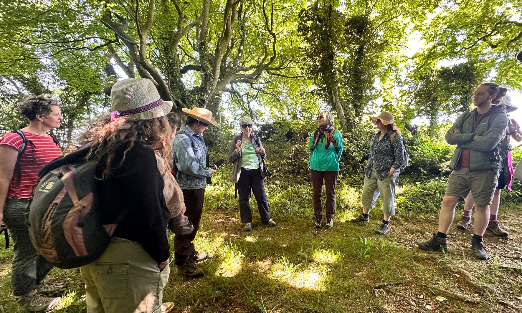 A group of people listen to a talk at Newmarket Plantation on the Stopping Places Walk