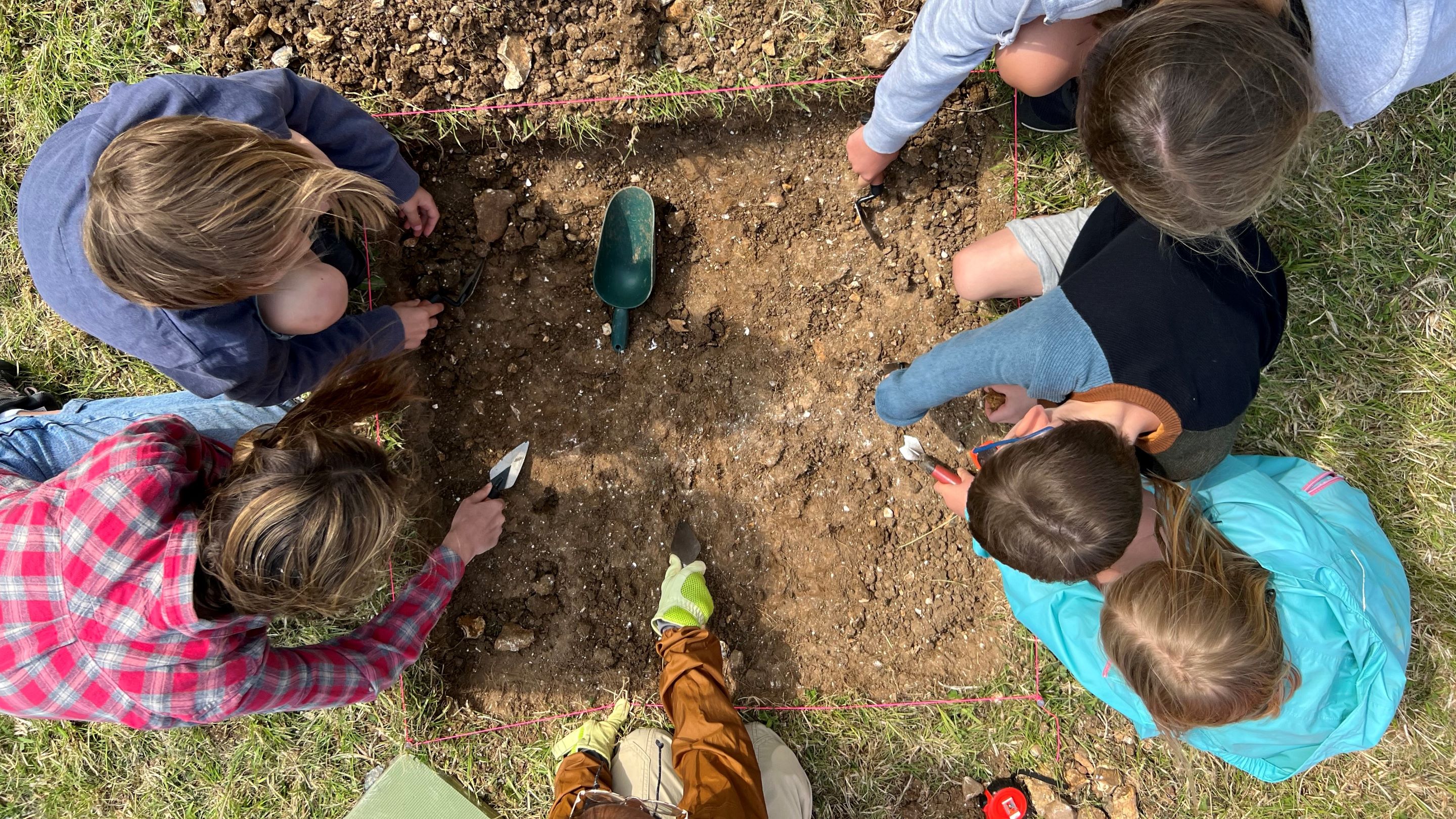 a group of children photographed from above as they carry out archaeological excavations