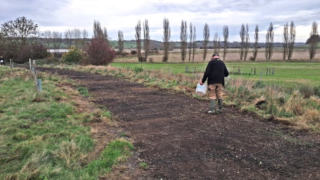 Shows a person sowing wildflower seeds