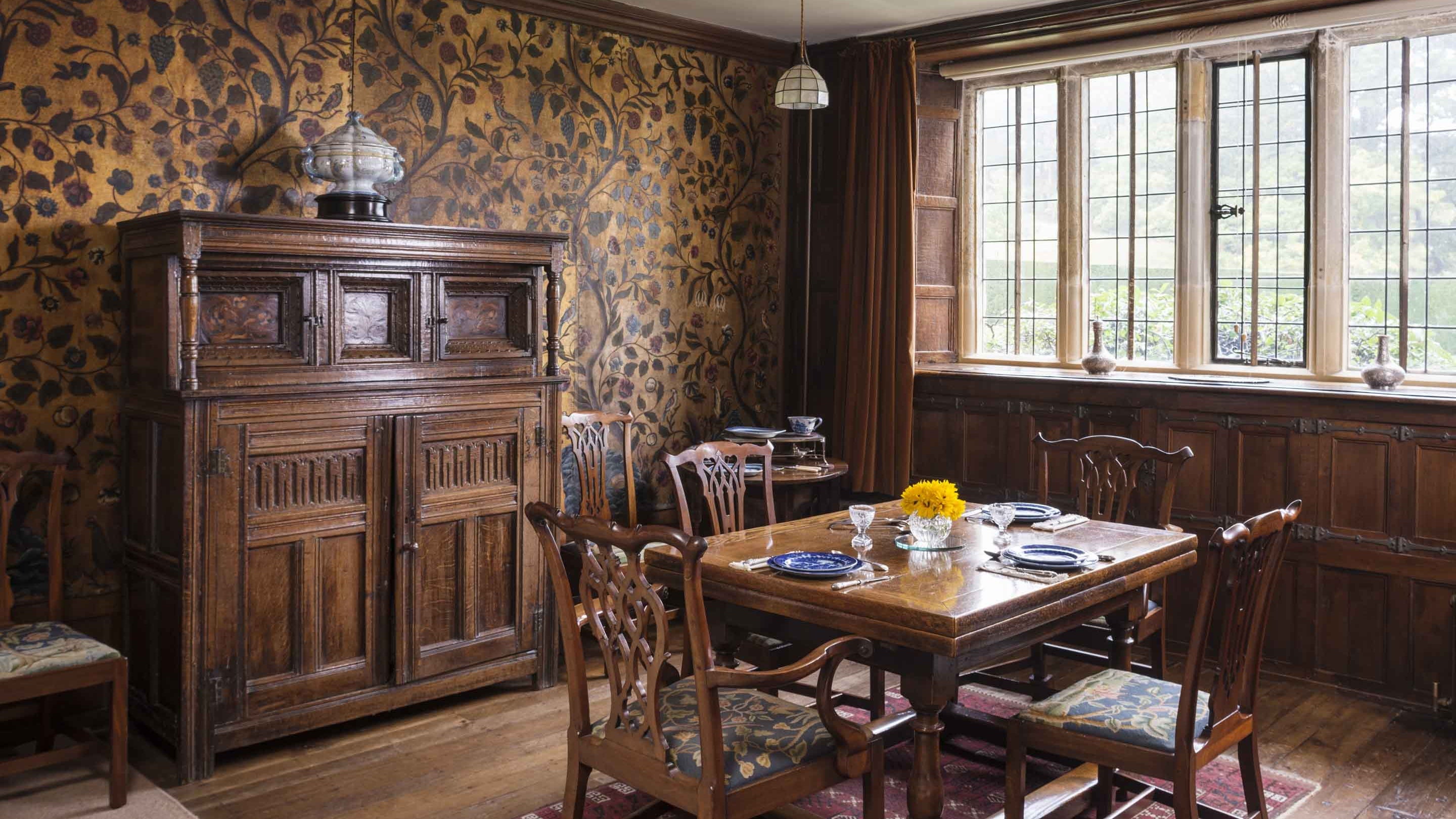 Sideboard, table and chairs in the dark wood-paneled dining room at Bateman's, East Sussex
