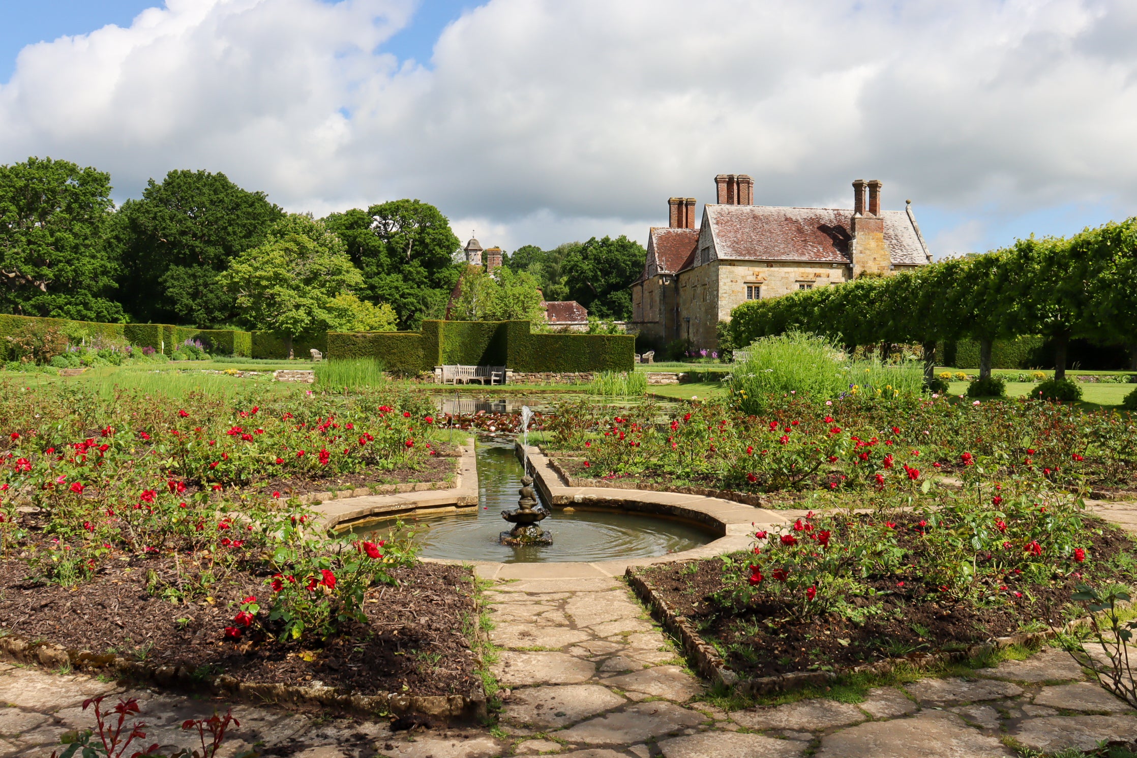 Looking over a bed of red and pink roses towards the Jacobean manor house.