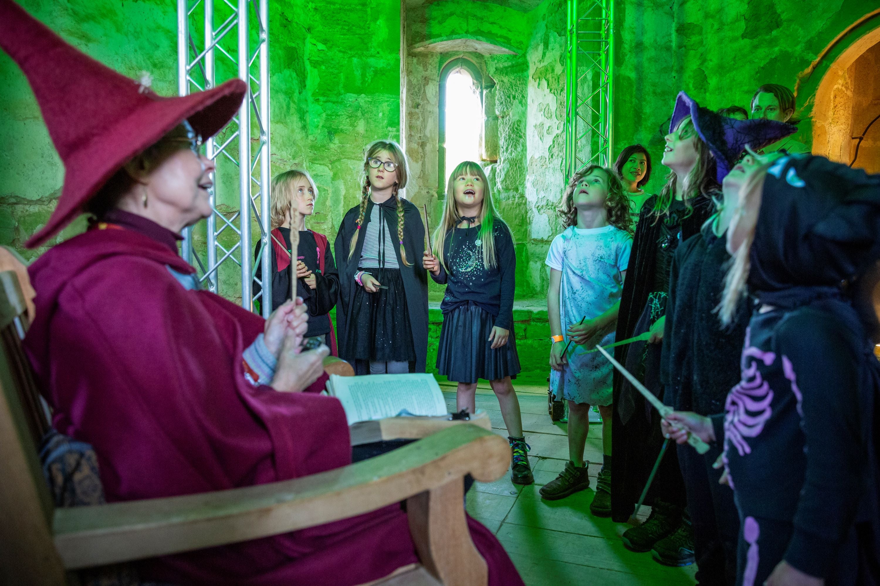 Families in fancy dress taking part in a thrilling Spell Quest to save the castle from the clutches of a wicked warlock during Halloween at Bodiam Castle, East Sussex