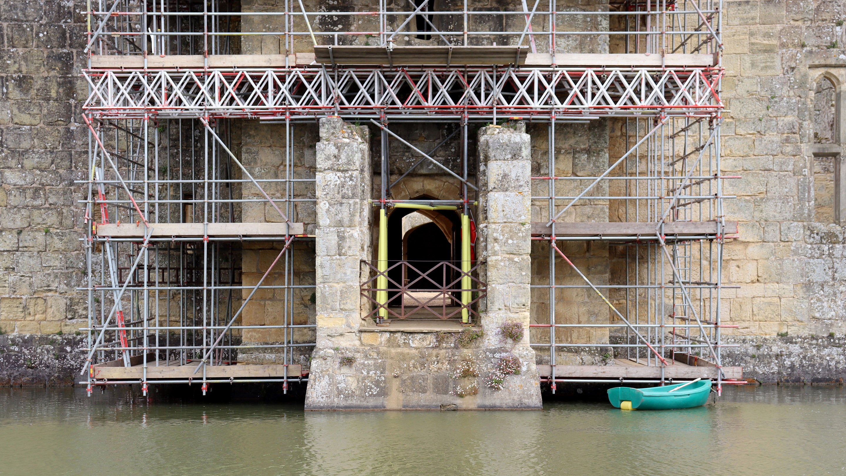 Scaffolding over a sandstone castle tower and moat