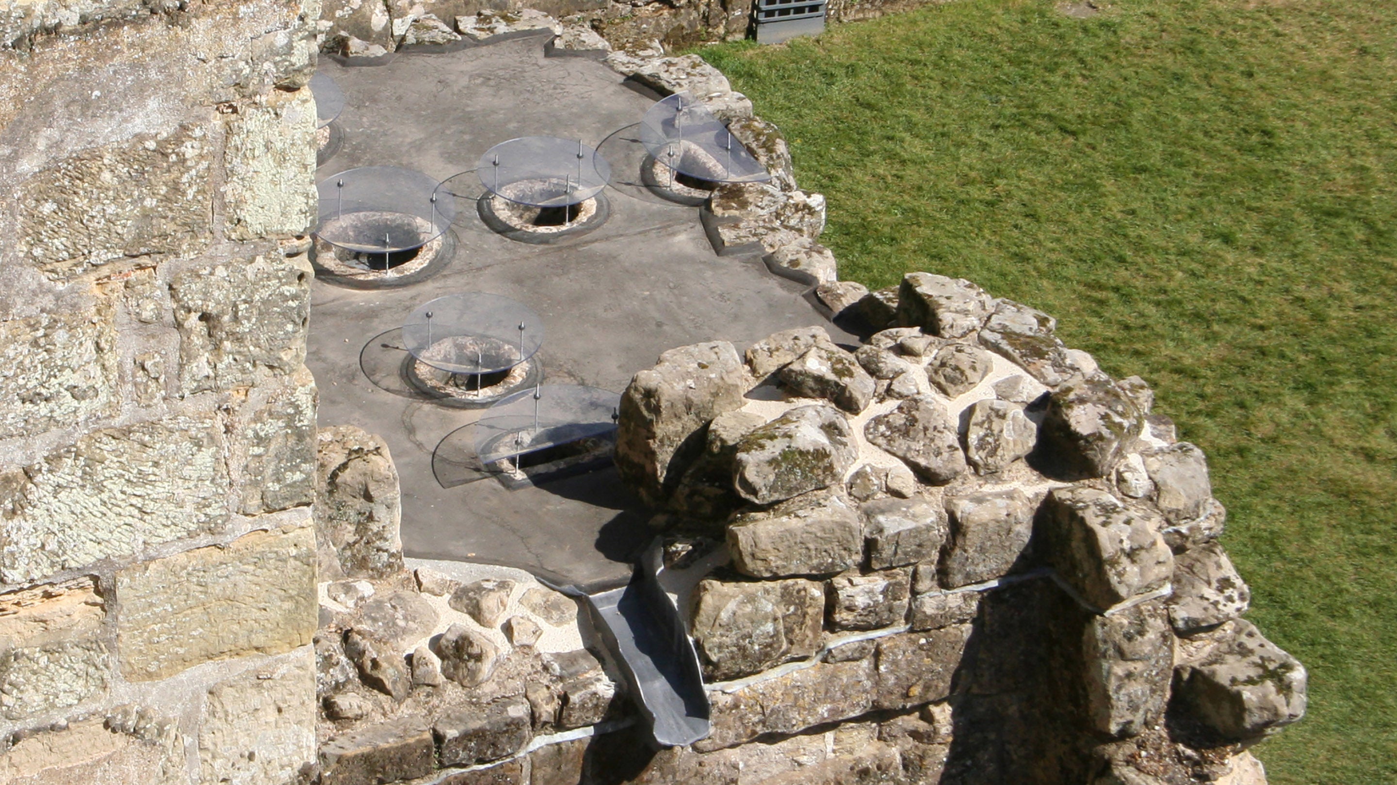 Murder holes in Bodiam Castle gatehouse, with new discs installed above each one for protection