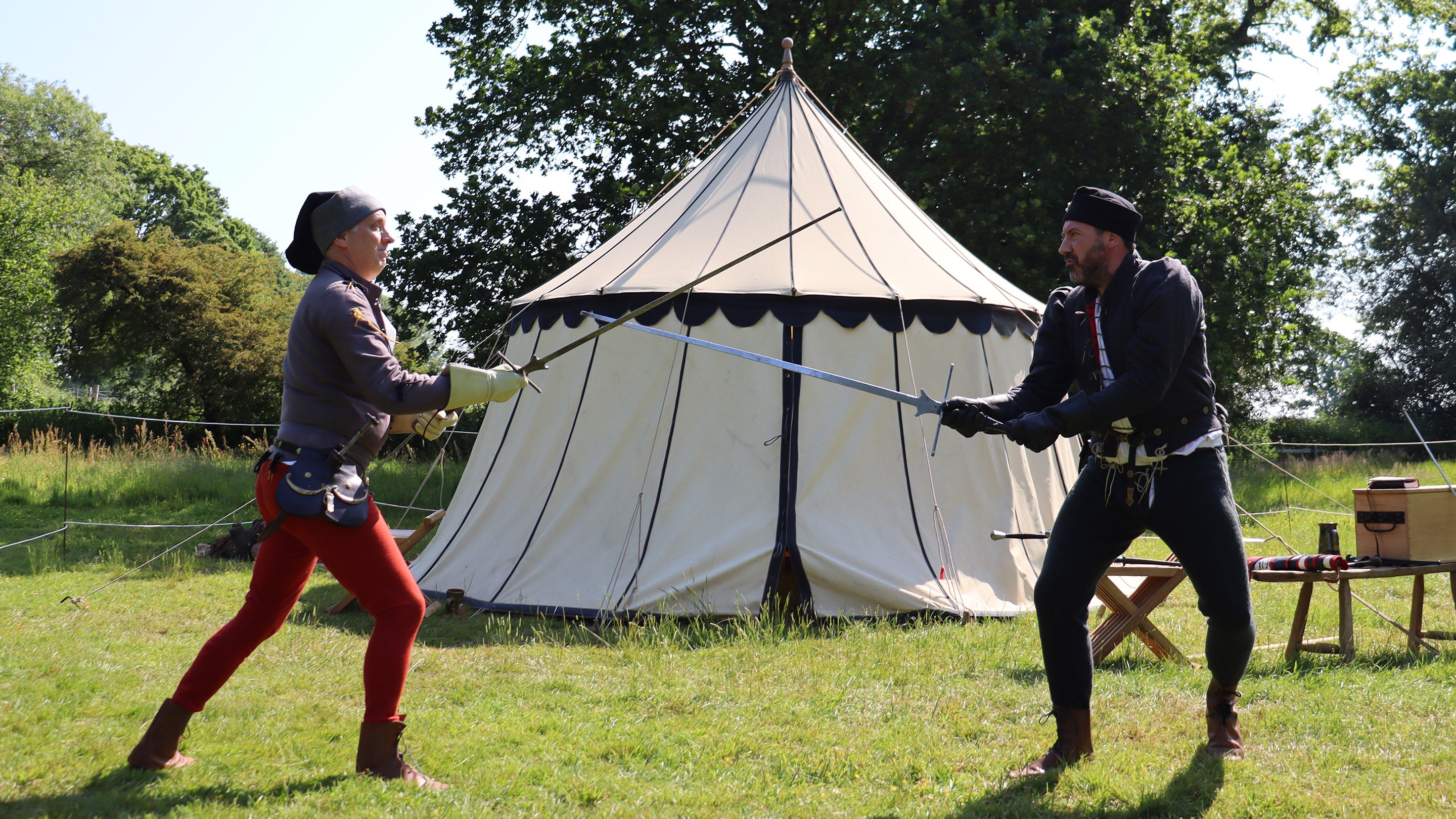 Members of Call to Arms in costume demonstrating medieval combat, with a tent in the background