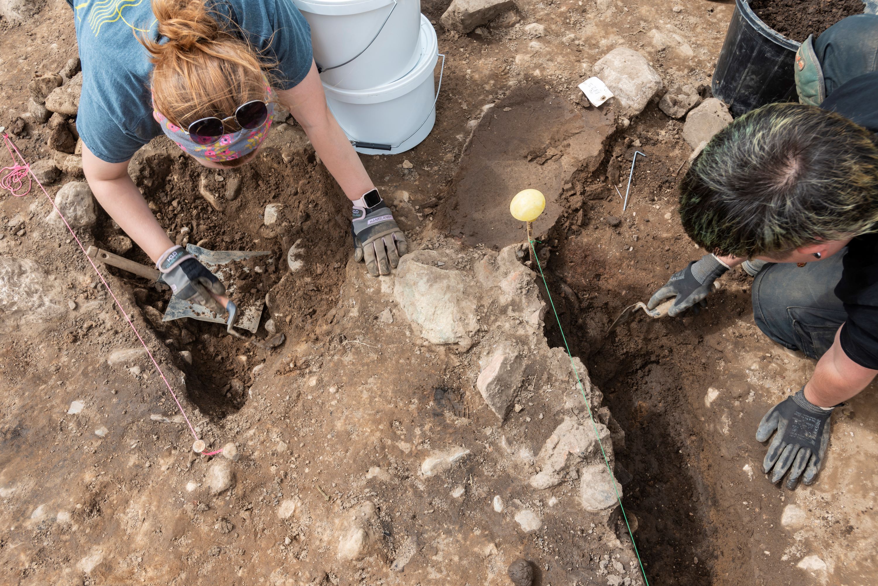 Volunteers kneeling over a dig site