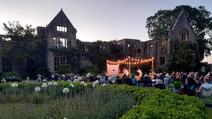 An evening theatre performance at sunset on the lawn in front of the ruins.